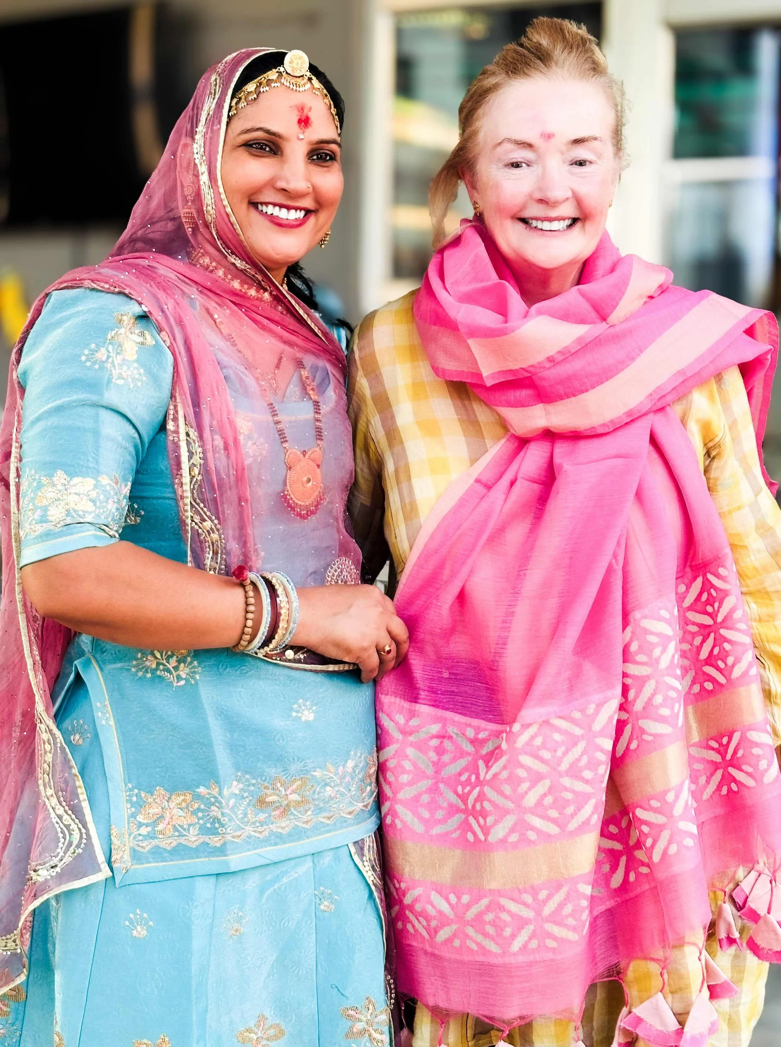 Bernadette O’Farrell and Ruma Devi smiling together at the GVCS compound, Barmer, Rajasthan, October 2025. Bernadette is wearing the pink cutwork dupatta gifted to her by Ruma Devi.