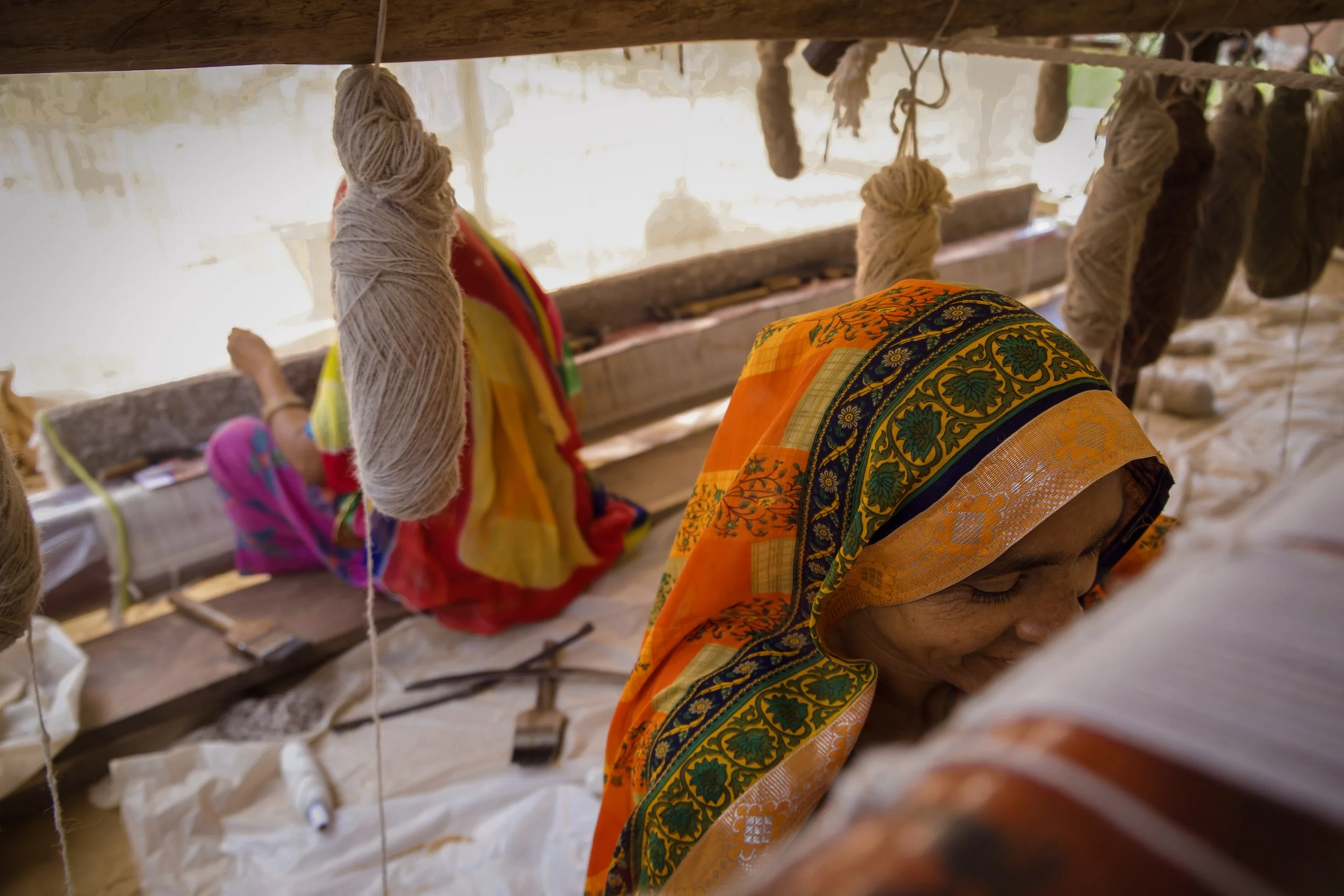 Women weaving rugs on traditional looms at a village craft collective outside Jaipur, Rajasthan