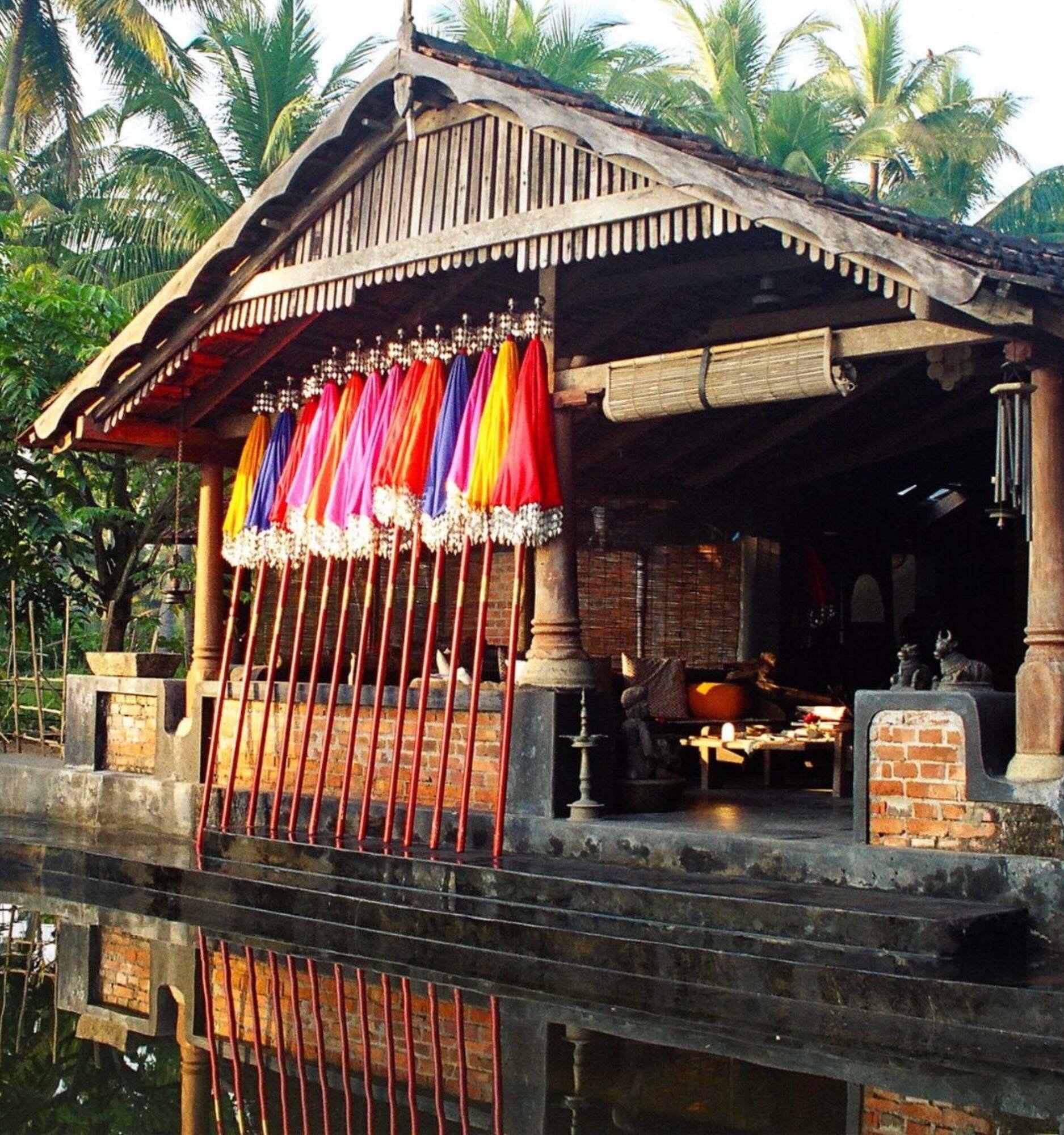Traditional Kerala waterside house with colourful parasols displayed outside.