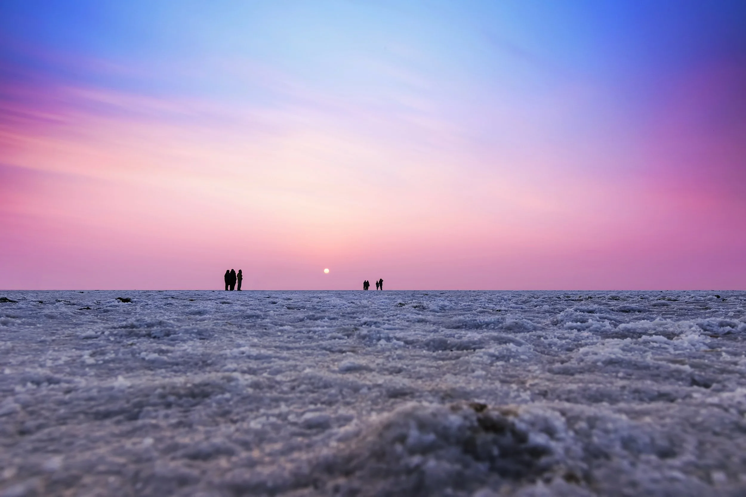 Sunset over the Rann of Kutch salt marsh with silhouetted figures, Gujarat - India with Bernadette