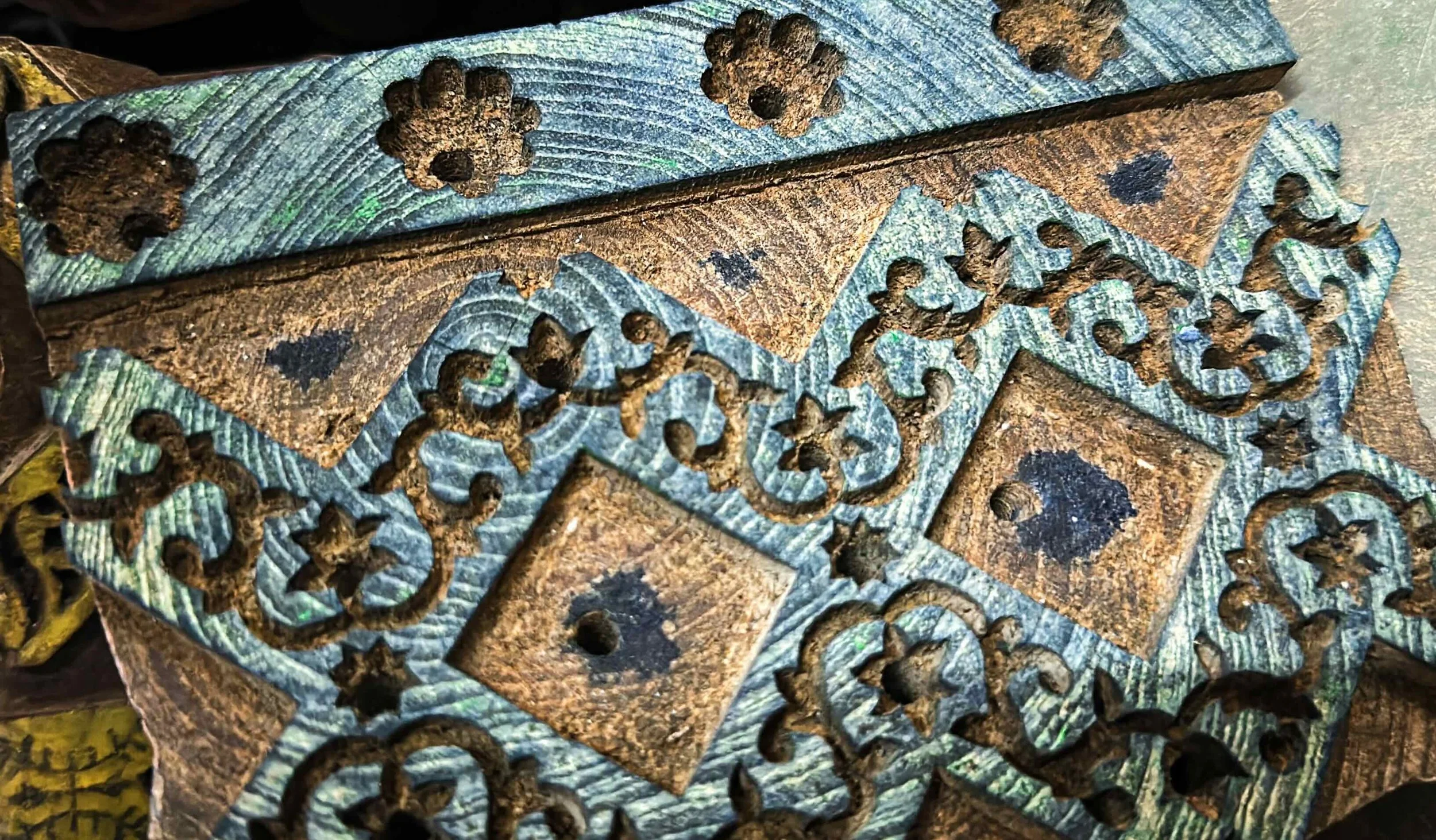 Close-up of a hand-carved ajrakh printing block from Khatri Sufiyan Ismail’s workshop - the carved surface worn smooth with years of use and saturated deep with accumulated indigo dye.