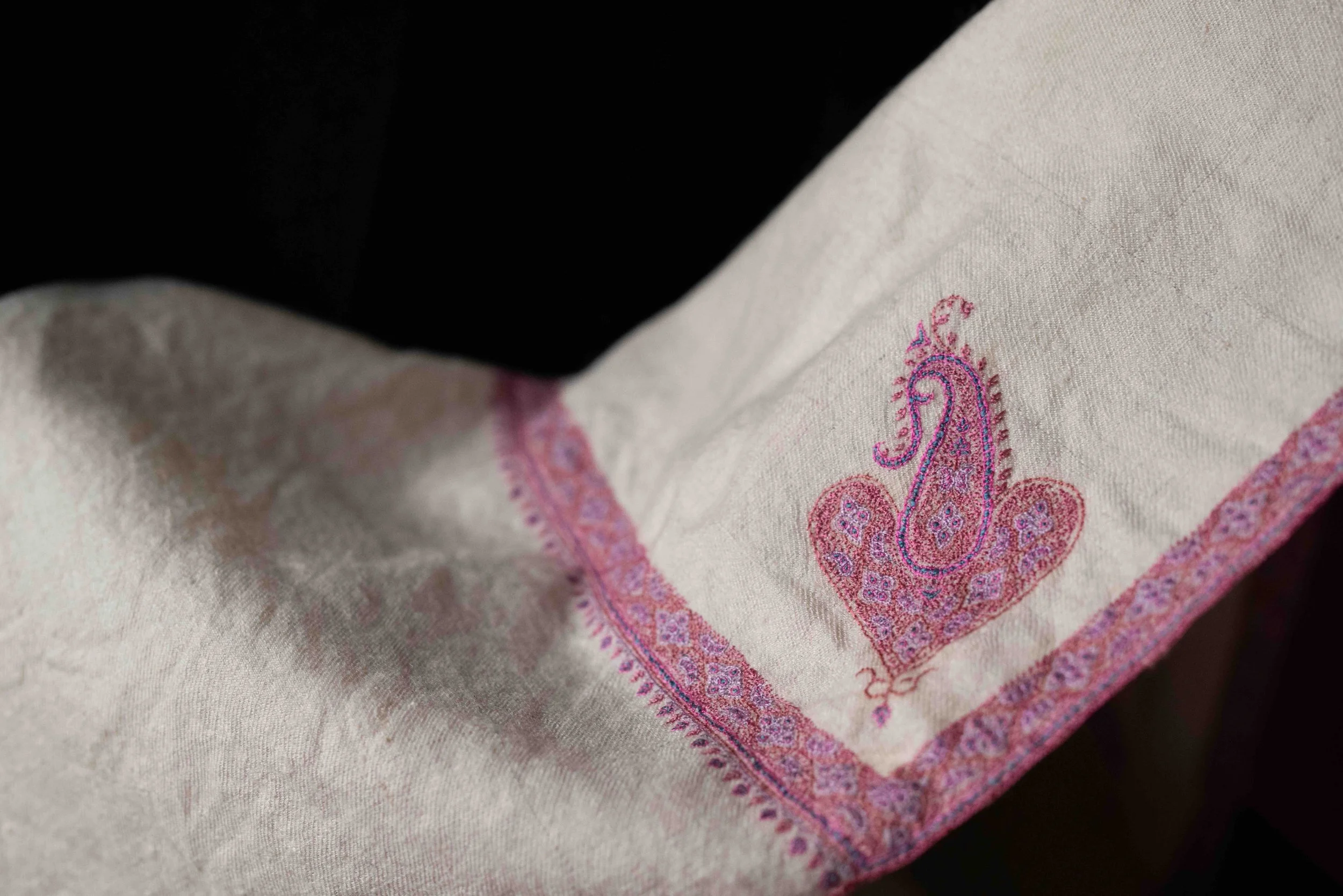 Fine Kashmiri shawl with hand-embroidered paisley motif at the corner, pale pashmina with pink border detail.