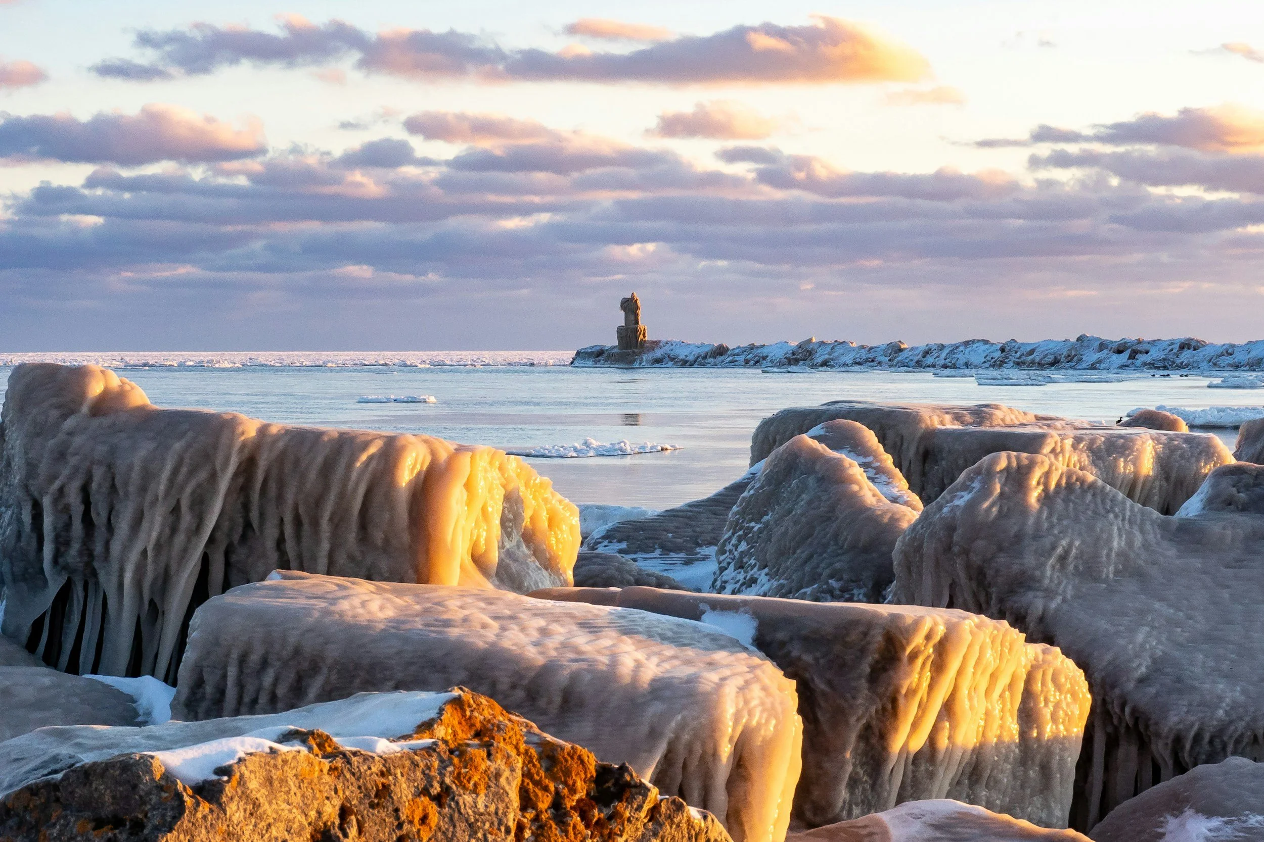 Frozen rocks and ice formations on a snowy shoreline with cloudy sky, symbolizing God’s strength and steadfast presence in life’s challenges.