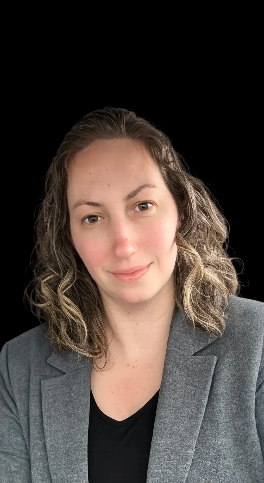 Portrait of the founder of Black River Customs LLC Nurse Consult in a gray blazer and black top on a black studio background