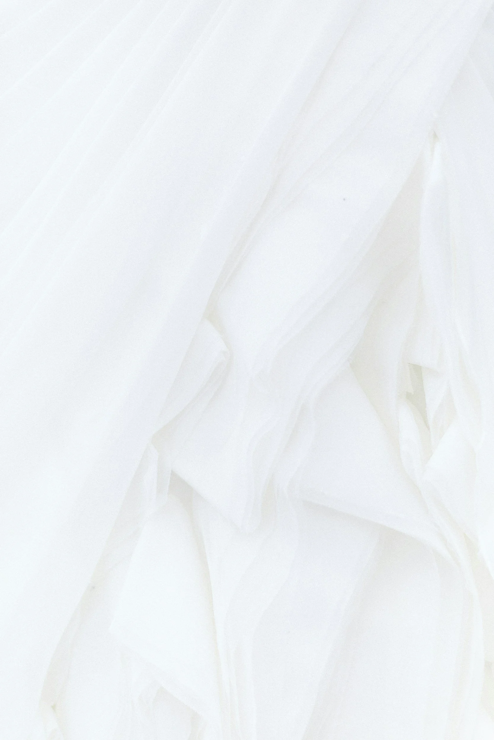 A sheet of crumpled white paper or fabric with soft shadows and folds.