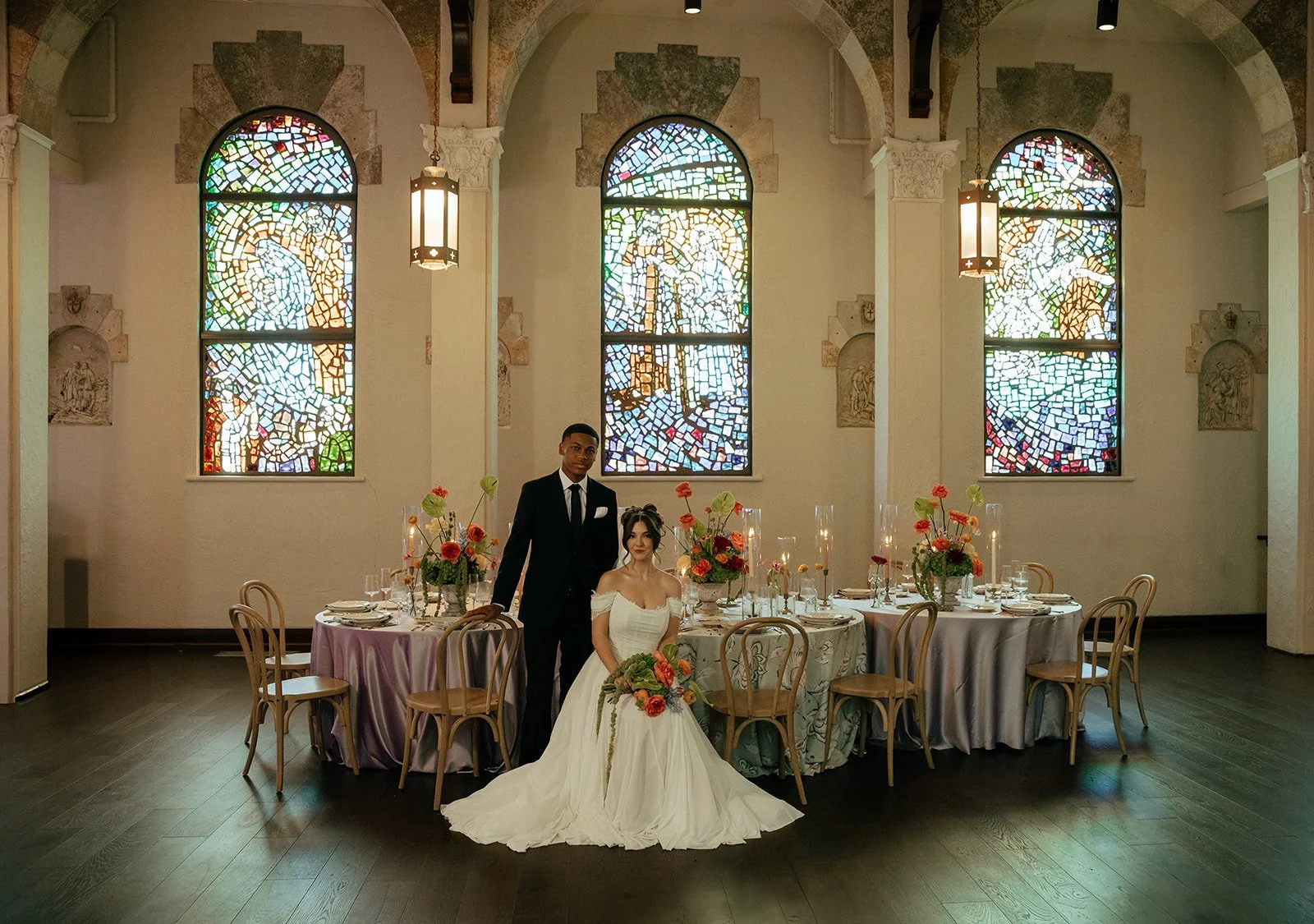 A bride and groom pose for a photo inside a church with stained glass windows, at Gather at Lake Wales Art Center, an Orlando Wedding Venue
