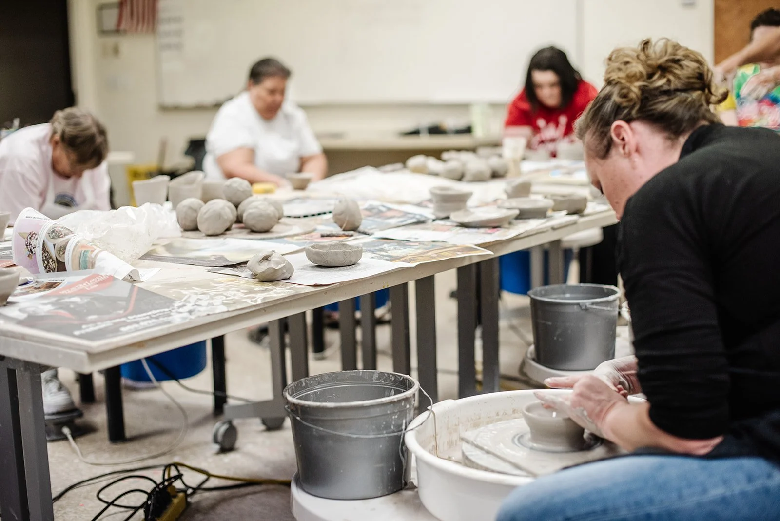 A diverse group of business people engaged in a meeting around a long conference table in a room decorated with artwork, books, and paintings of horses and cowboys.