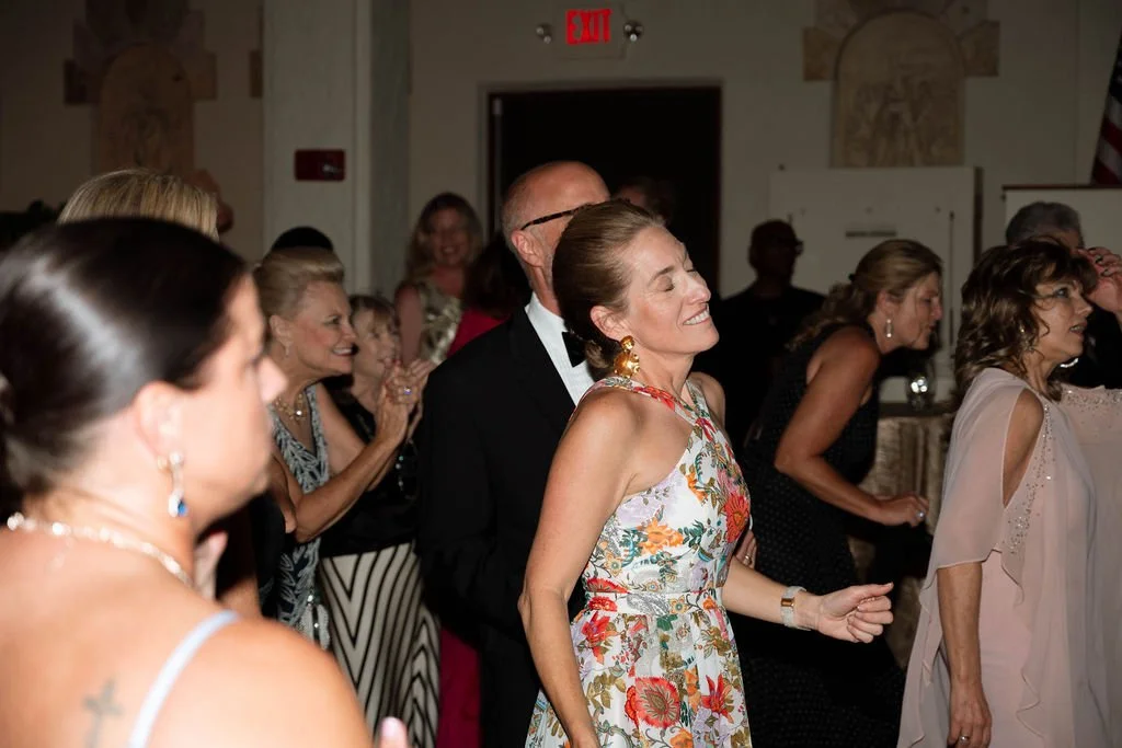 People dancing and enjoying themselves at a celebration or party in a decorated indoor venue.