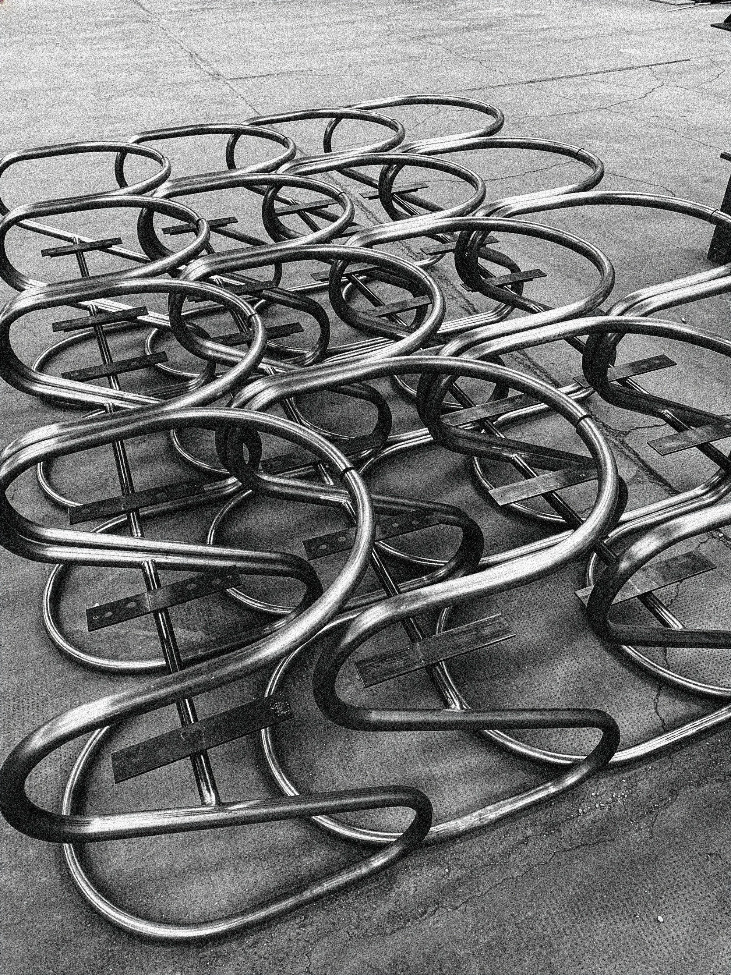 Conjunto de estructuras tubulares de acero curvado, dispuestas sobre el suelo durante el proceso de fabricación de mobiliario. SILLA S