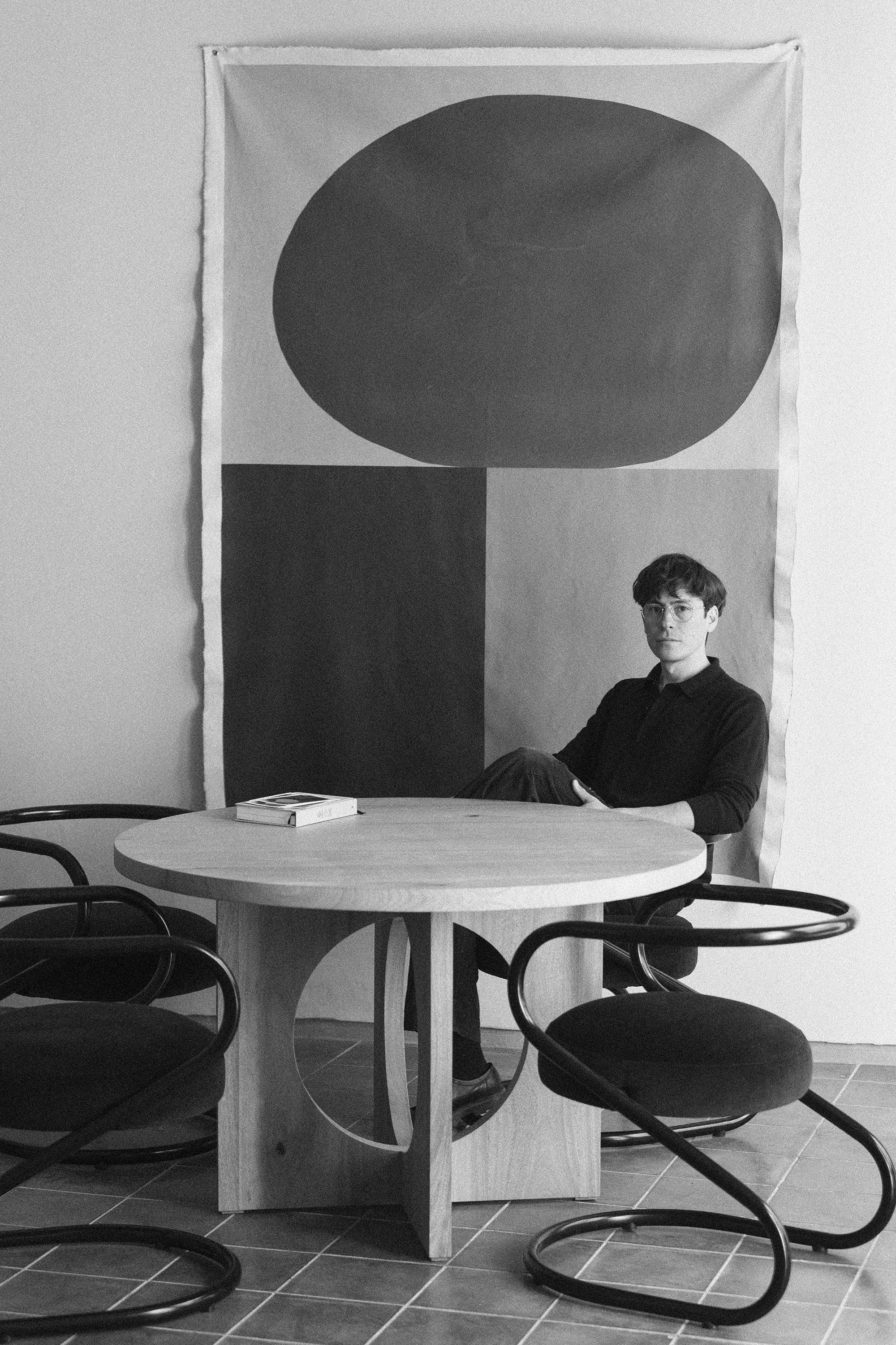 Foto de Milton Monsalvo en su estudio con Mesa OTO y Sillas S con tapiz diseñado por el mismo