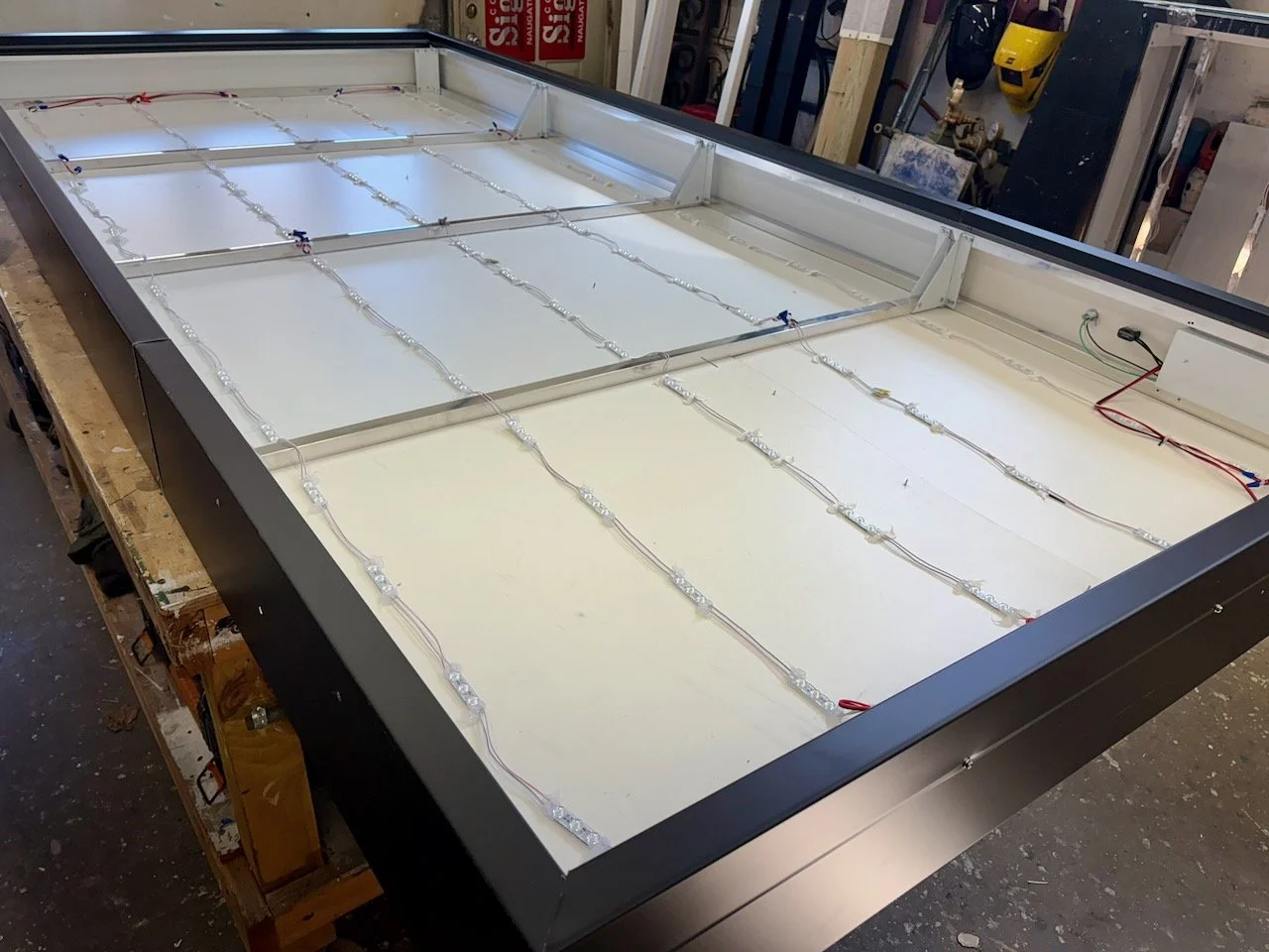 A large LED display frame with bundled LED strips and wiring inside a workshop.