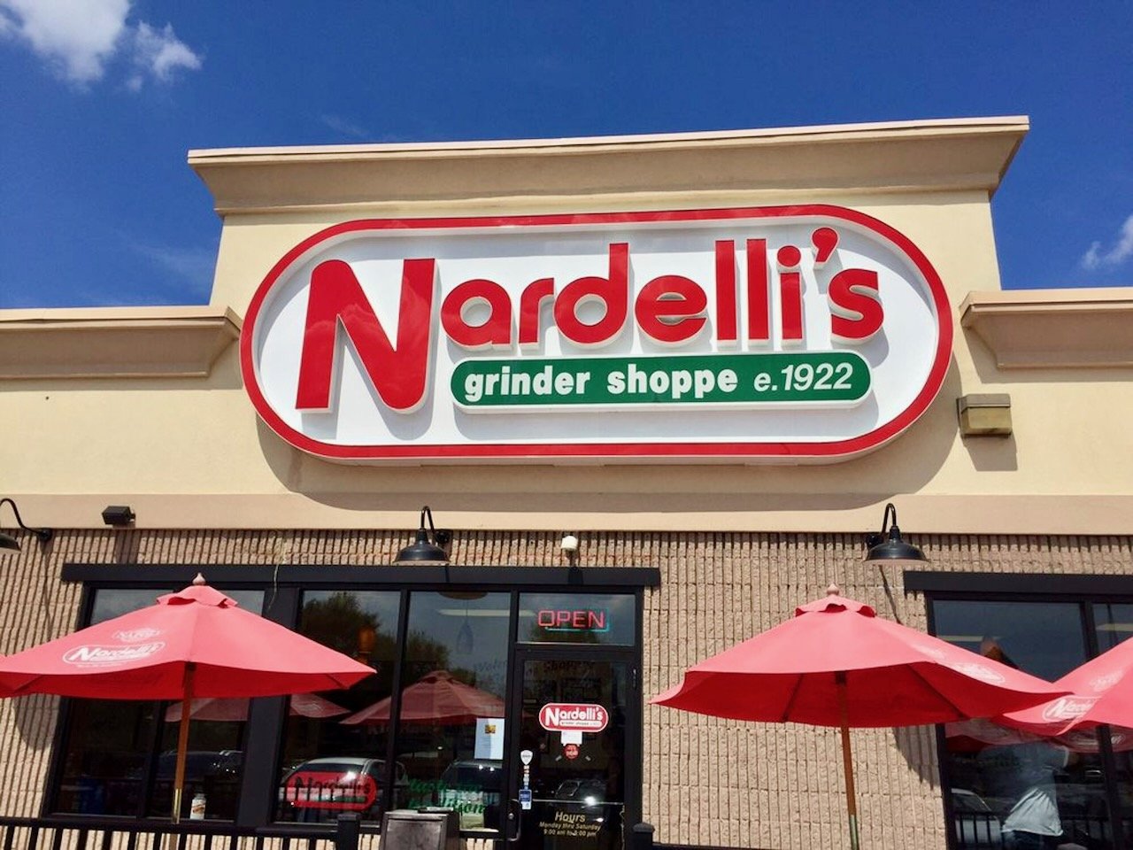 Nardelli's grinder shoppe storefront with a large sign and red umbrellas outside