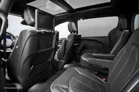 Interior of a vehicle showing black leather seats and a rear entertainment screen.
