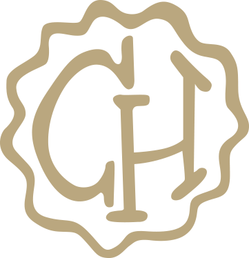 A monogram logo with the initials G and H inside a scalloped circle.
