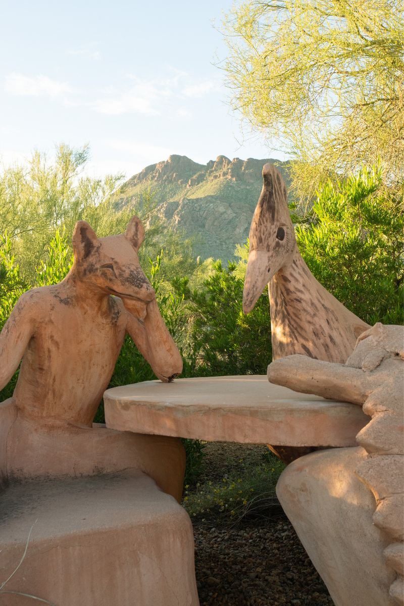 Sculptures by Kit Schweitzer of desert creatures gathered around a table in front of Cat Mountain
