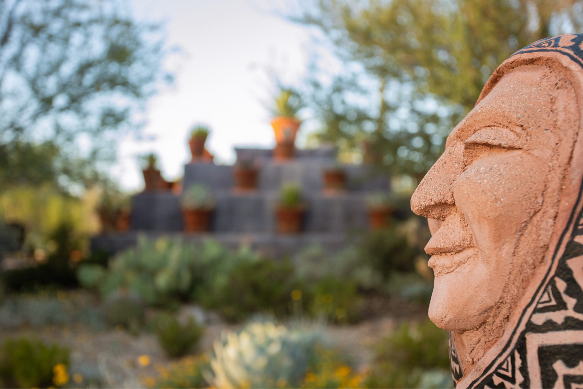 A close up of a sculpture at The Inn of an elderly woman, with the cactus pyramid behind her