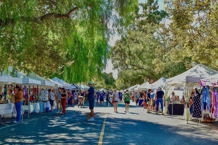 A vibrant morning at the Claremont Forum Farmers and Artisans Market in the Claremont Village, where local shopping supports the Prison Library Project.