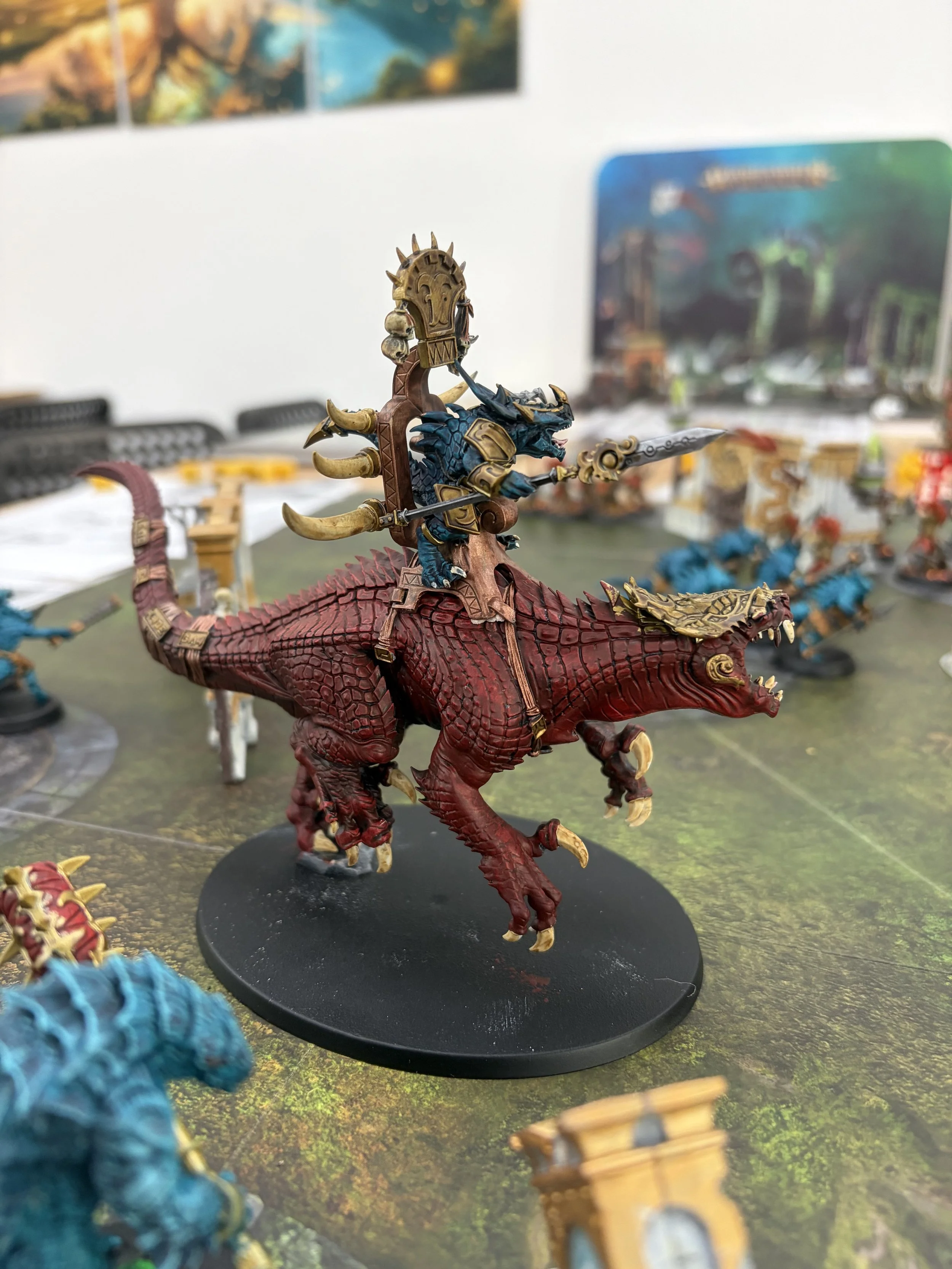 Miniaturfigur eines schildkrötengestaltigen Drachen mit einem Reiter, der ein Schwert hält, auf einem Sockel auf einem Spieltisch.