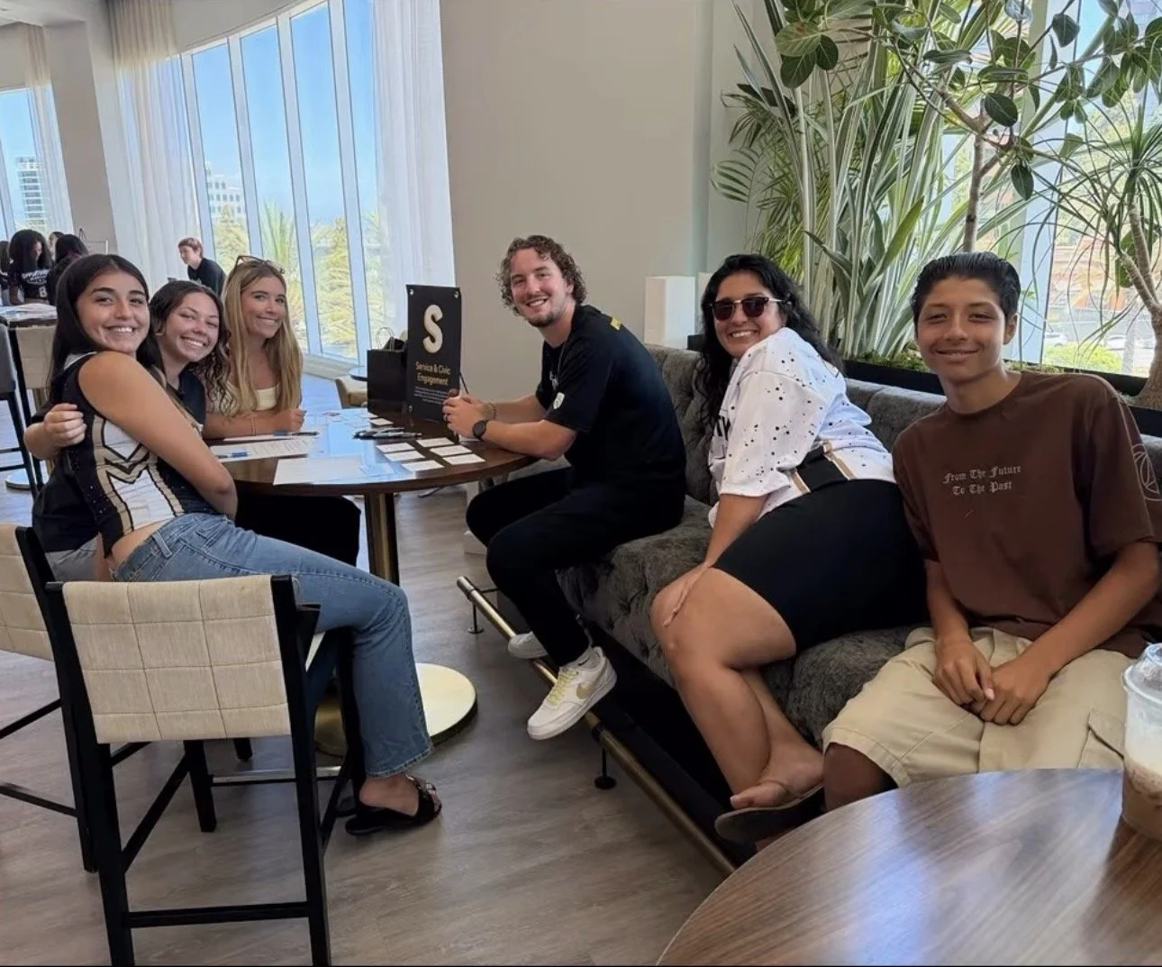 Opportunity Academy student-athletes and a mentor smiling together around a table during an OA program session