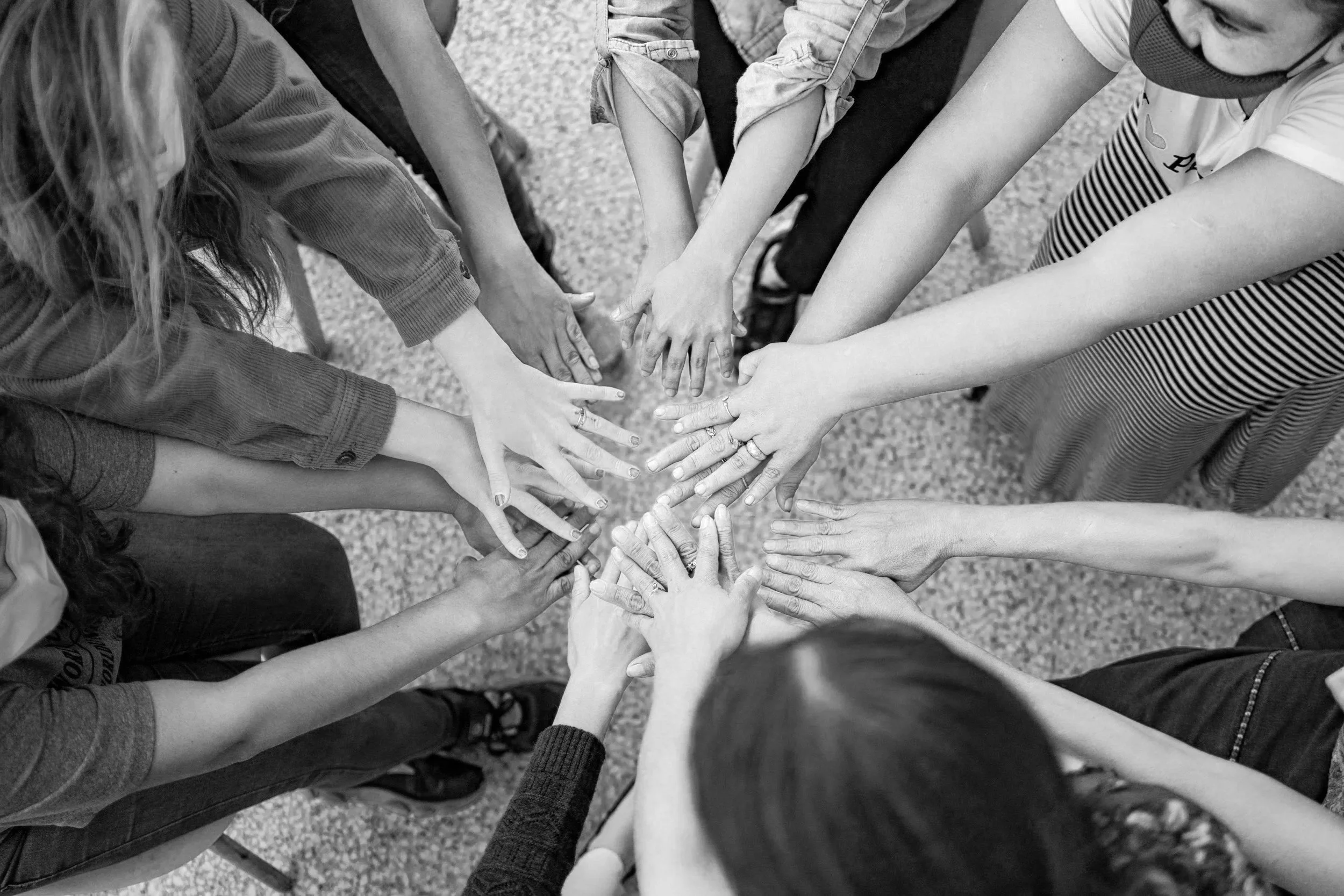 A group of diverse people placing their hands together in a circle to symbolize unity and teamwork.