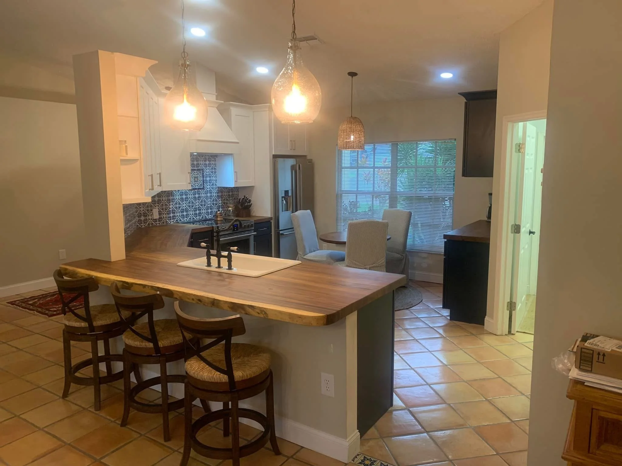 After: MichaelAngela Properties transformed it - refrigerator moved to the right corner, new Costa Rican wood countertops, custom Spanish hand-painted tiles, added coffee bar cabinets, and a cozy seating area at the bar. Bright, functional, and styli