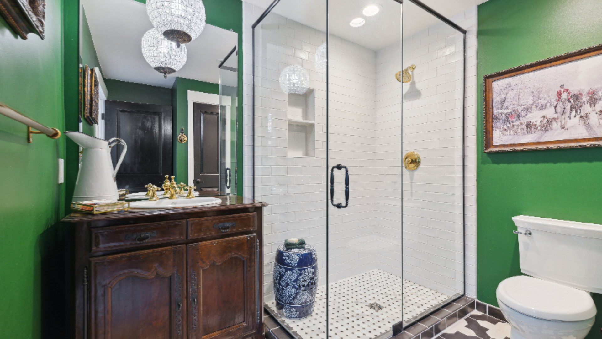Emerald Bathroom - Vivid green walls make a striking statement in this bath, balanced by a white subway-tiled glass shower and antique cherry wood vanity console Gold fixtures, globe pendant lighting, and a framed equestrian print add refined, expect