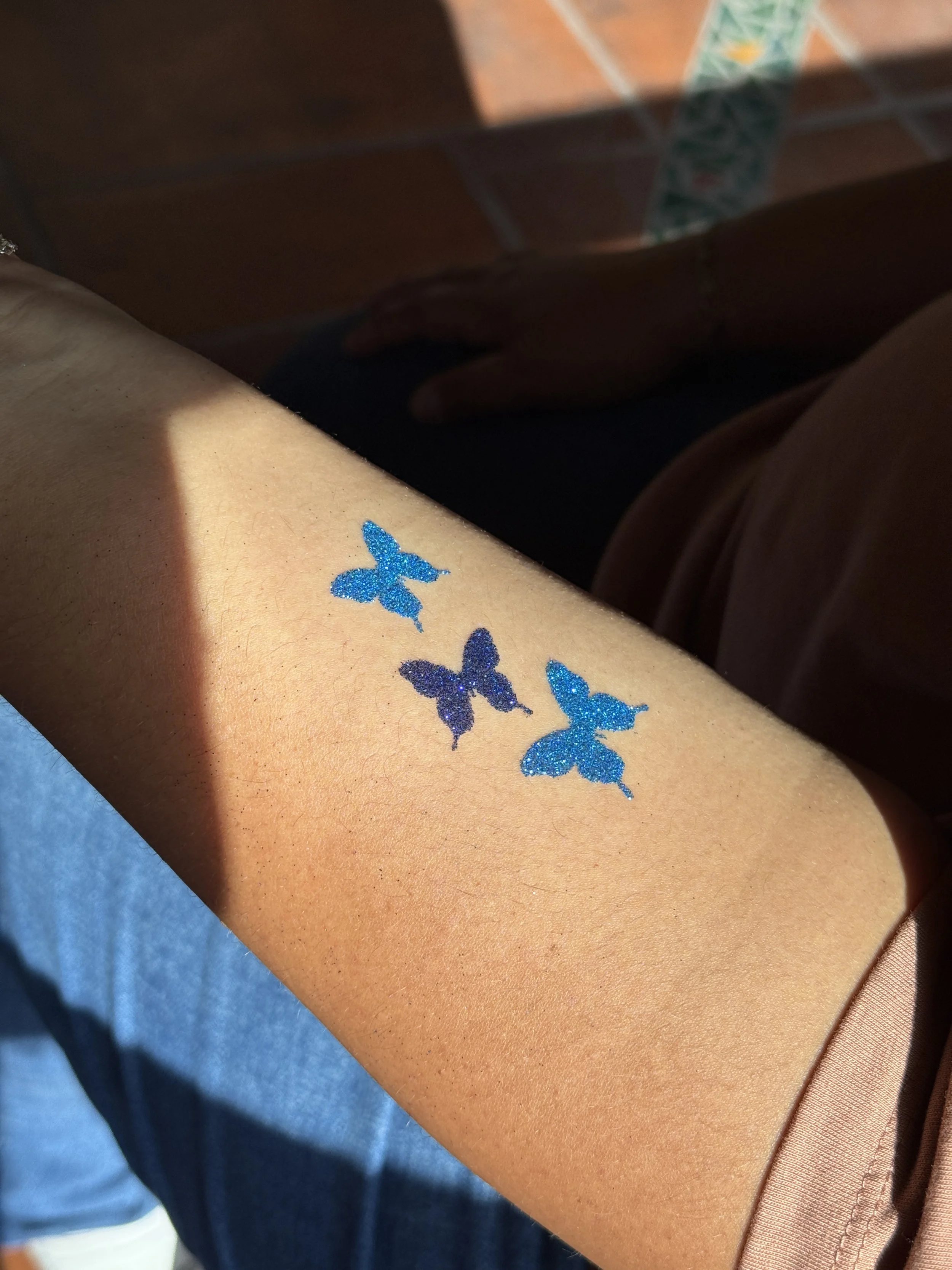 Blue butterfly glitter tattoo on arm