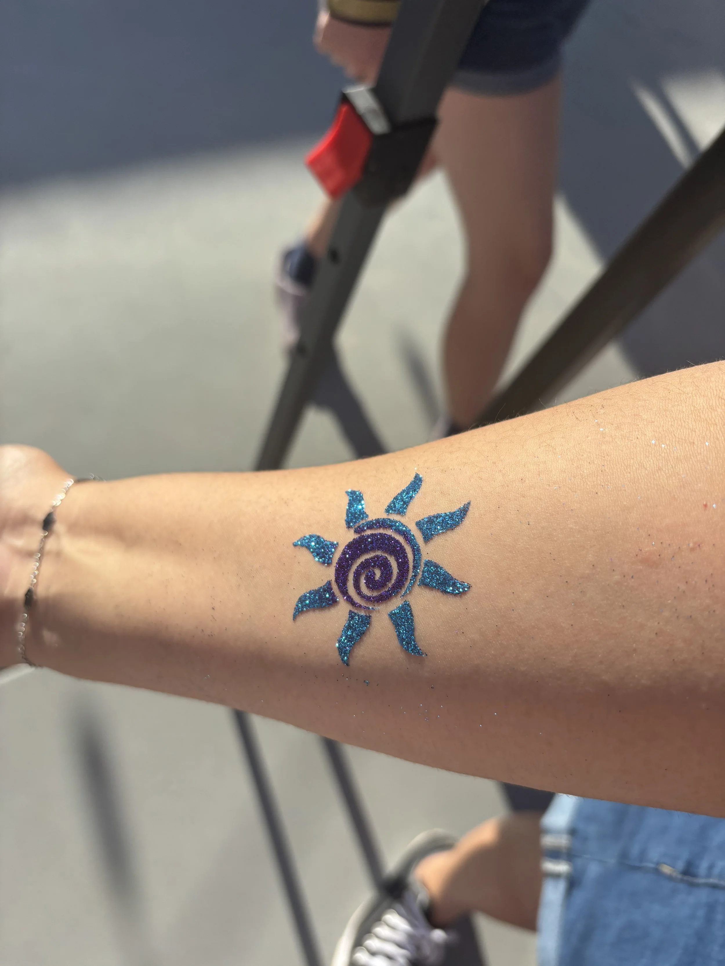 blue and purple sun tattoo on arm
