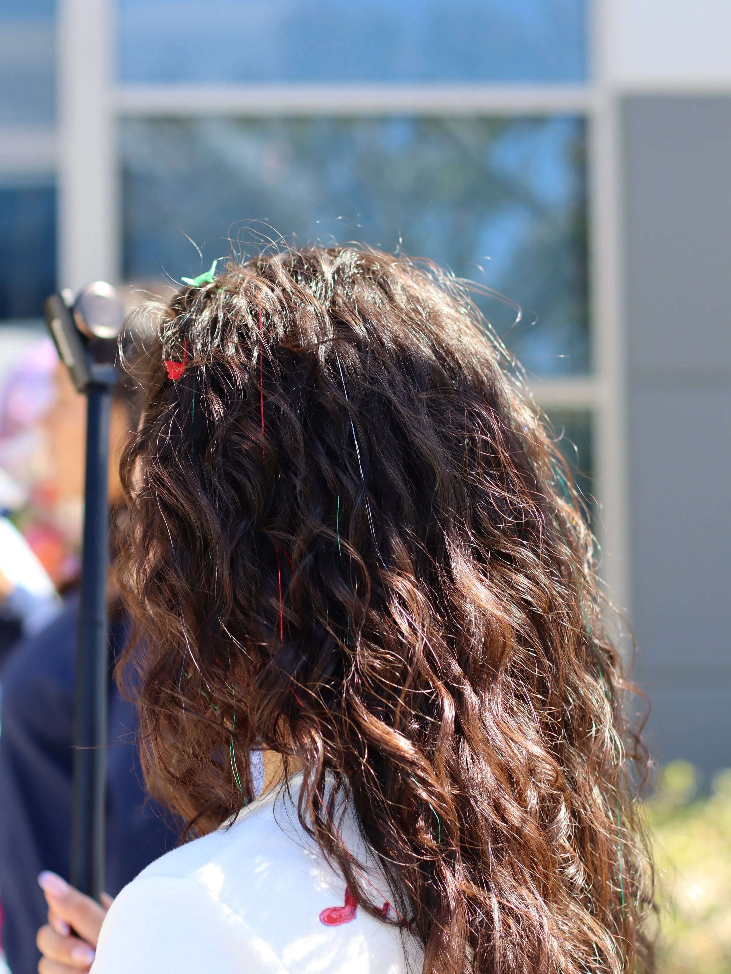 brunette with naturally curly hair with red, green, and silver tinsel for mexican pride