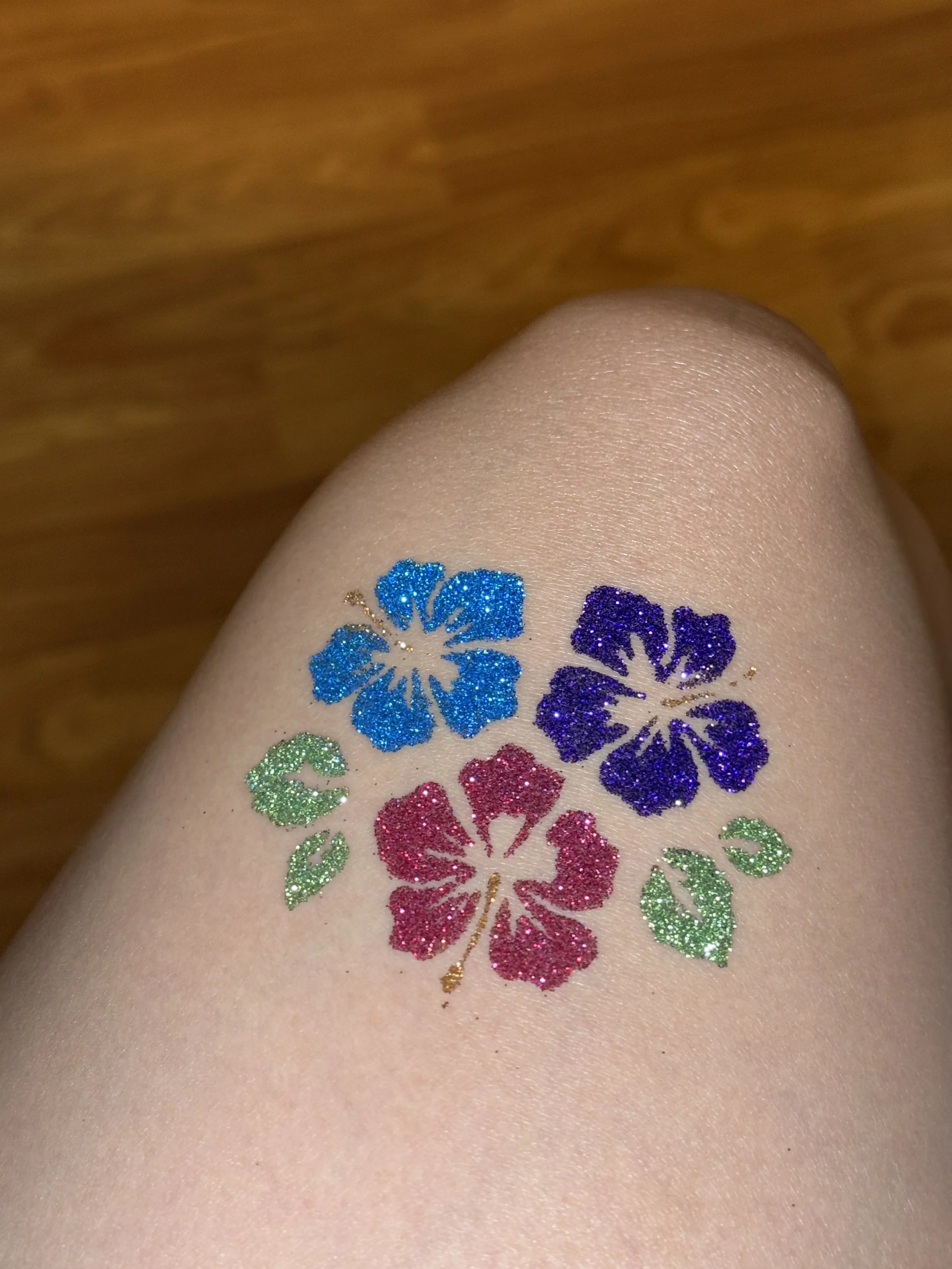 pink purple and blue aloha flowers on leg glittery tattoo