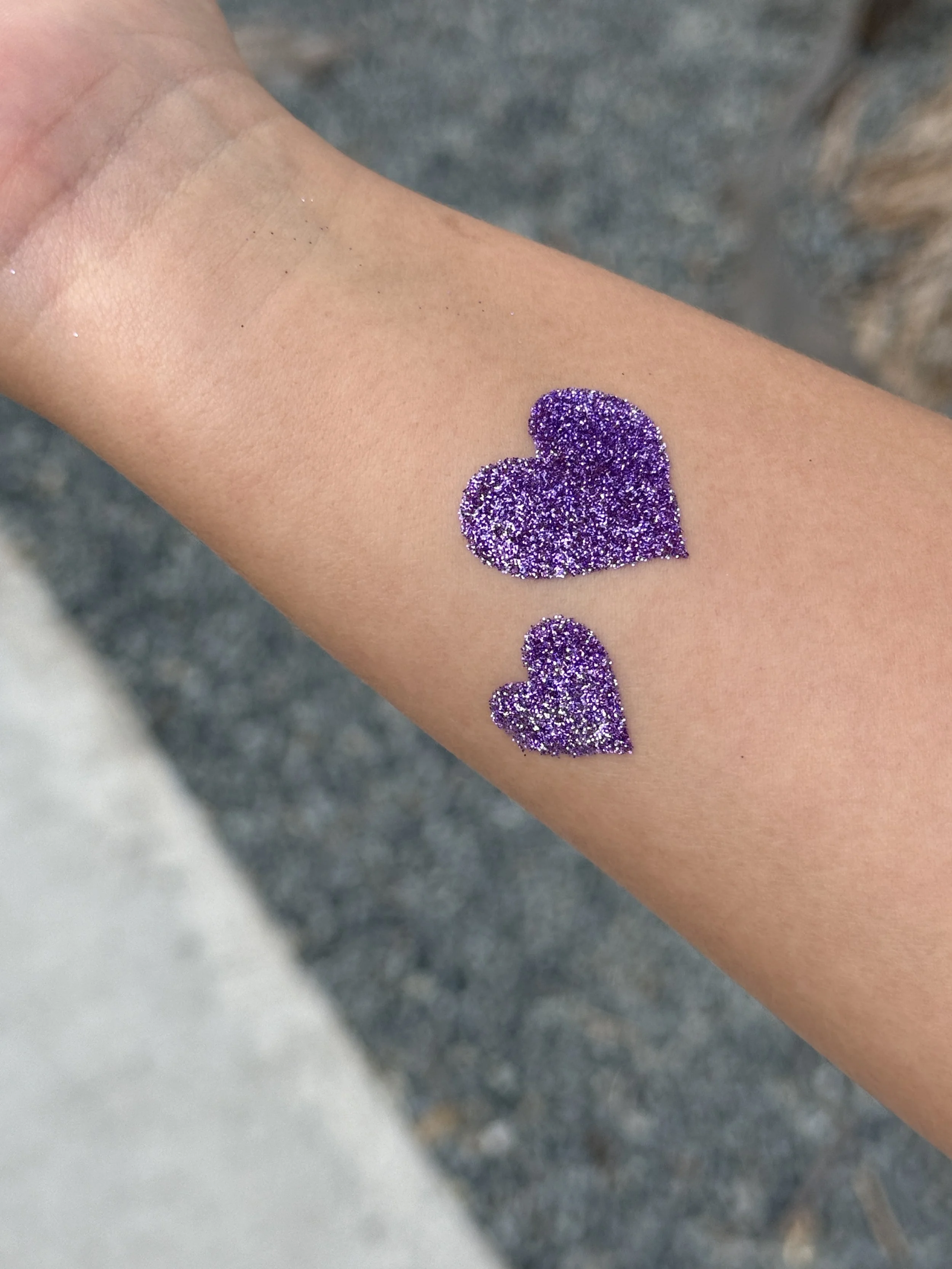 purple glitter tattoo on young girl arm