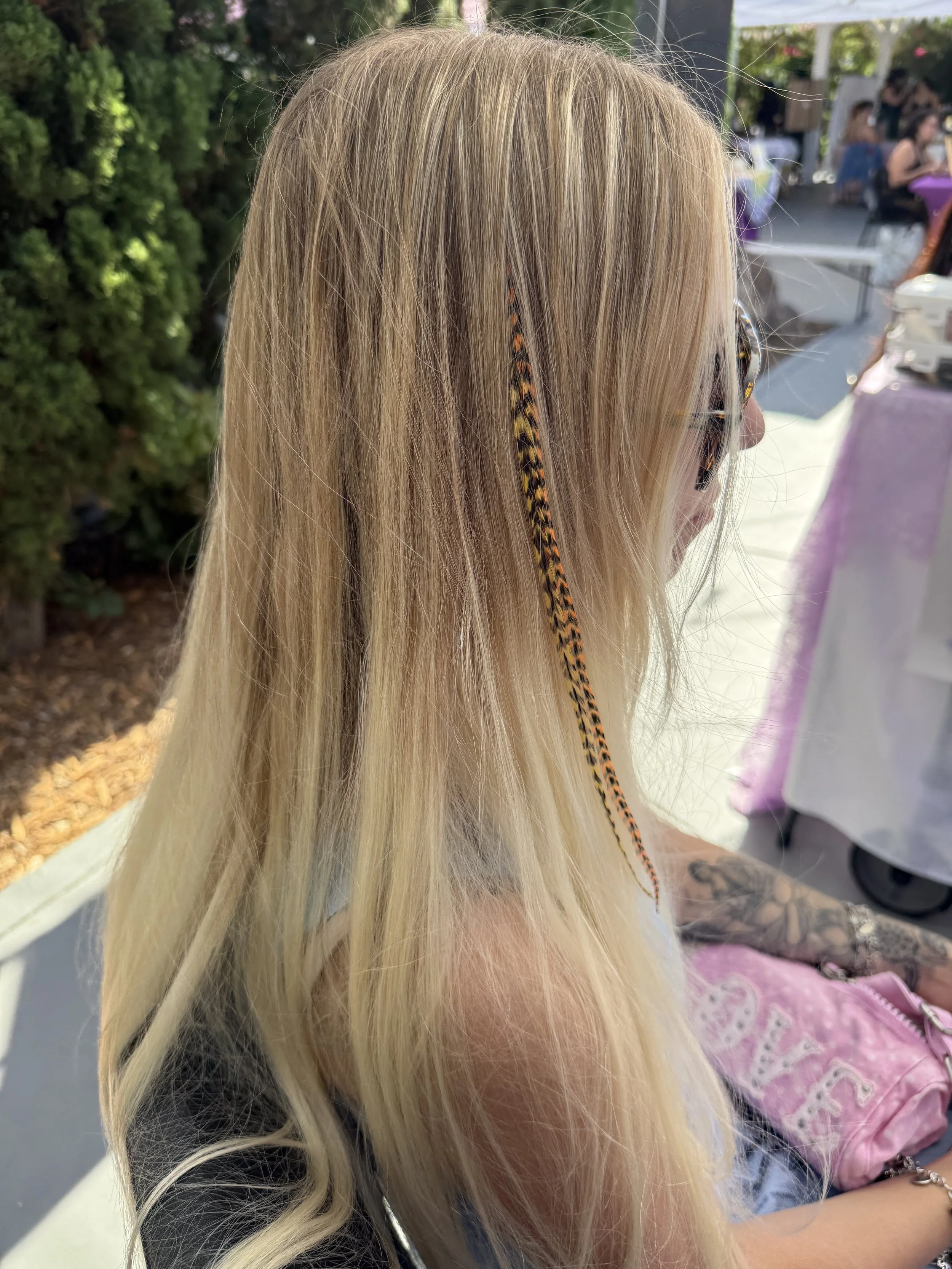 orange and yellow feathers in long blonde hair