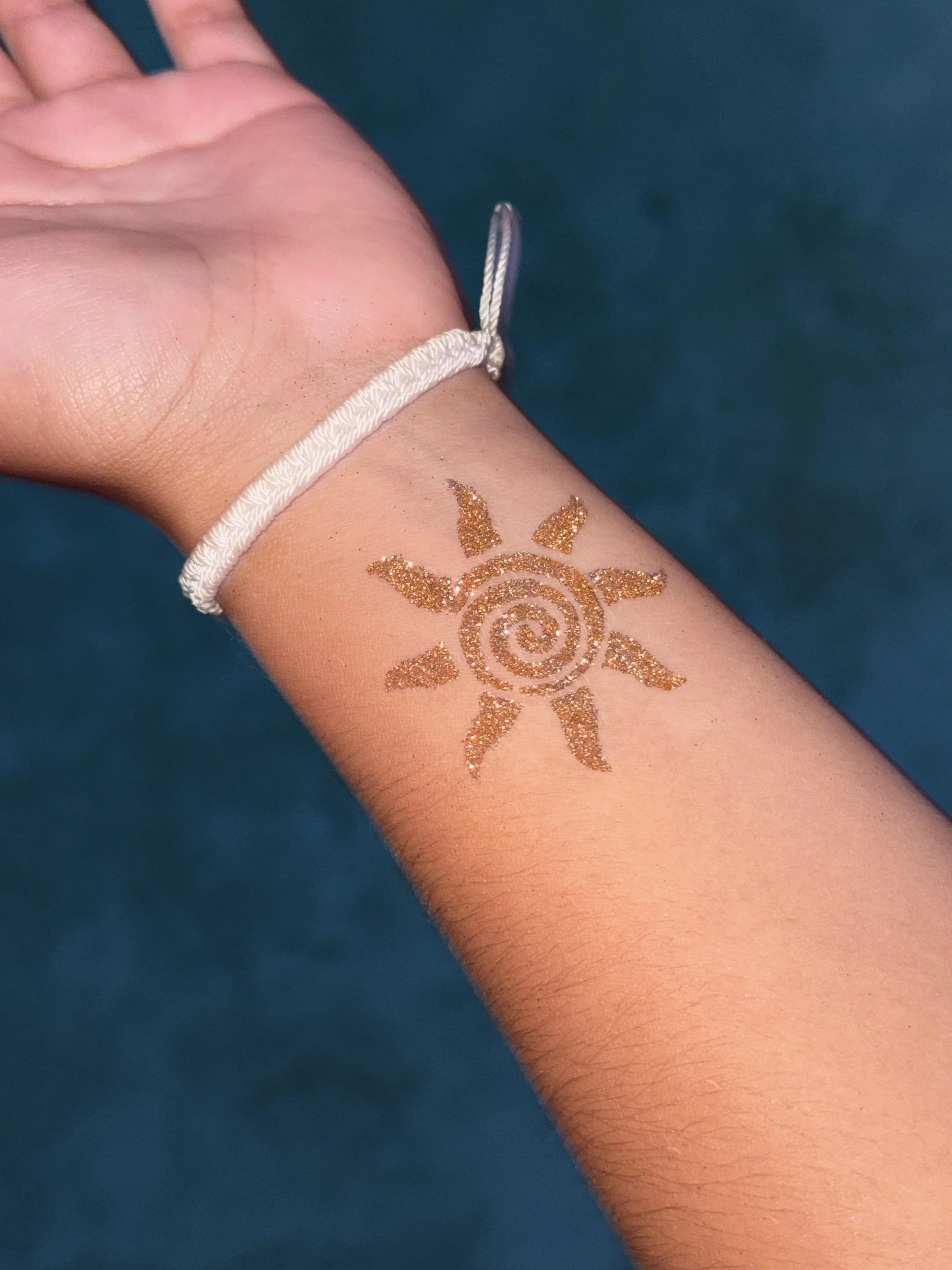 Glitter tattoo sun design on wrist