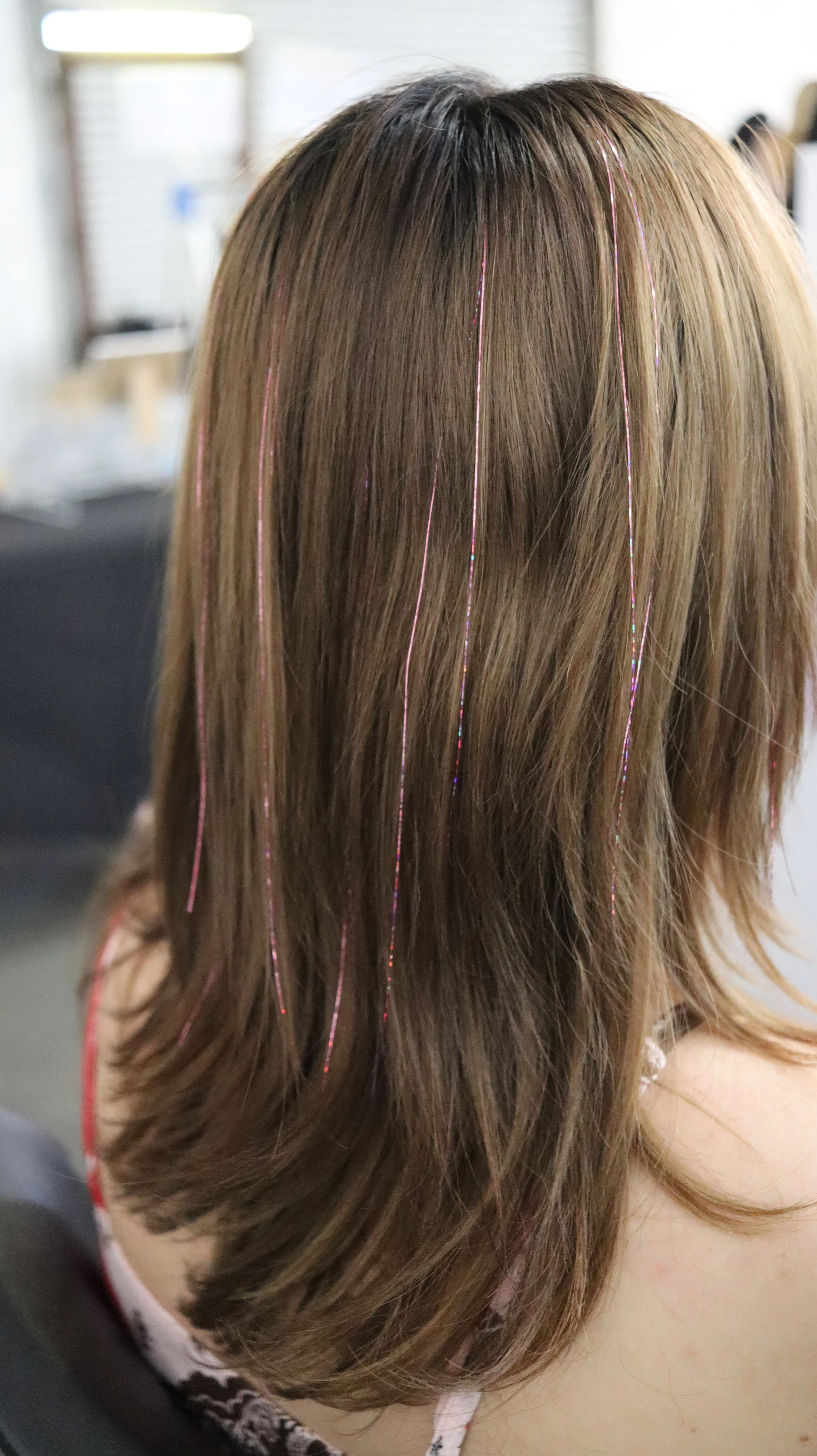 Pink hair tinsel strands in light brown hair