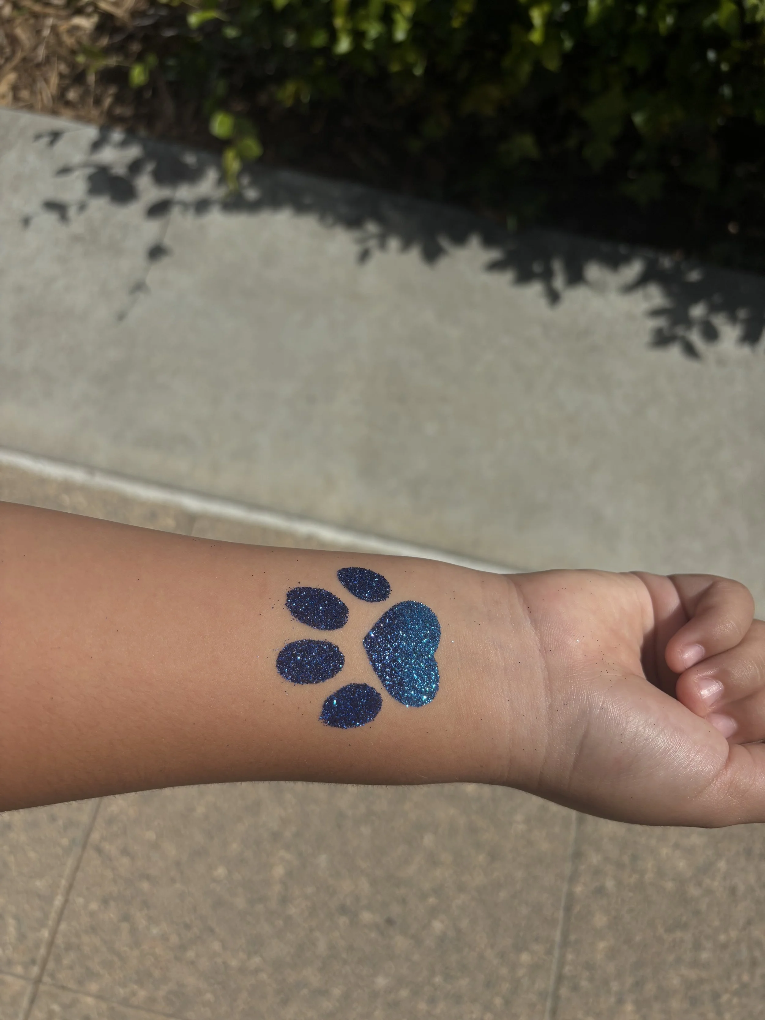 Dog paw glitter design tattoo in blue on kids arm