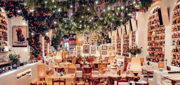Decorated restaurant interior with hanging greenery, purple flowers, string lights, framed photos, and wooden tables, representing the upscale hospitality environments served by DC Global Talent recruitment specialists.