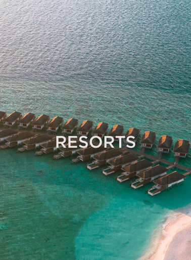 Overwater bungalows at a tropical resort with turquoise water and sandy beach, representing luxury hospitality destinations served by DC Global Talent recruitment specialists.