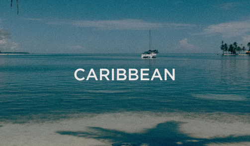 Calm Caribbean ocean with sailboat and palm trees, reflecting the luxury resort destinations within the hospitality industry served by DC Global Talent.