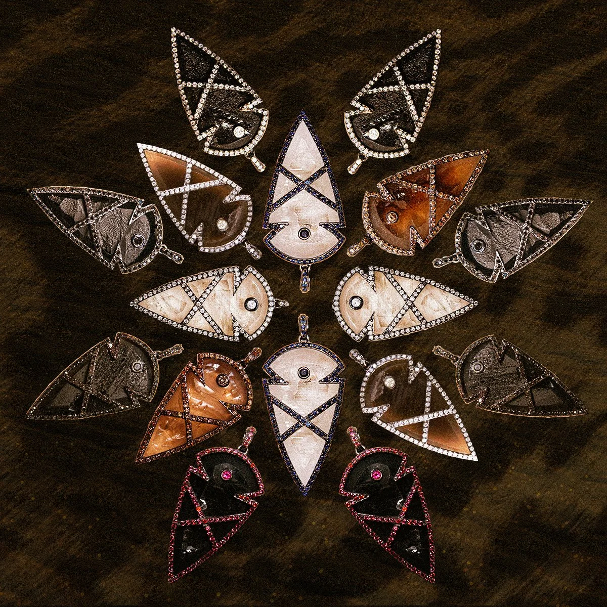 An array of different fine arrowhead jewelry amulets : featuring hand carved obsidian, clear quartz, smoky quartz, and lapis - surrounded in diamonds.