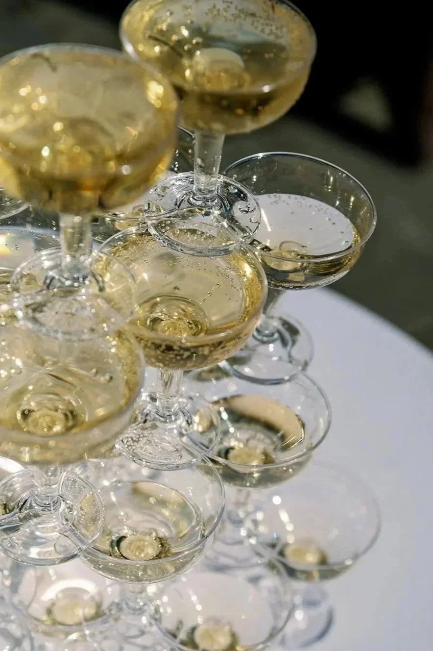 Multiple champagne glasses filled with sparkling champagne arranged in a pyramid shape.