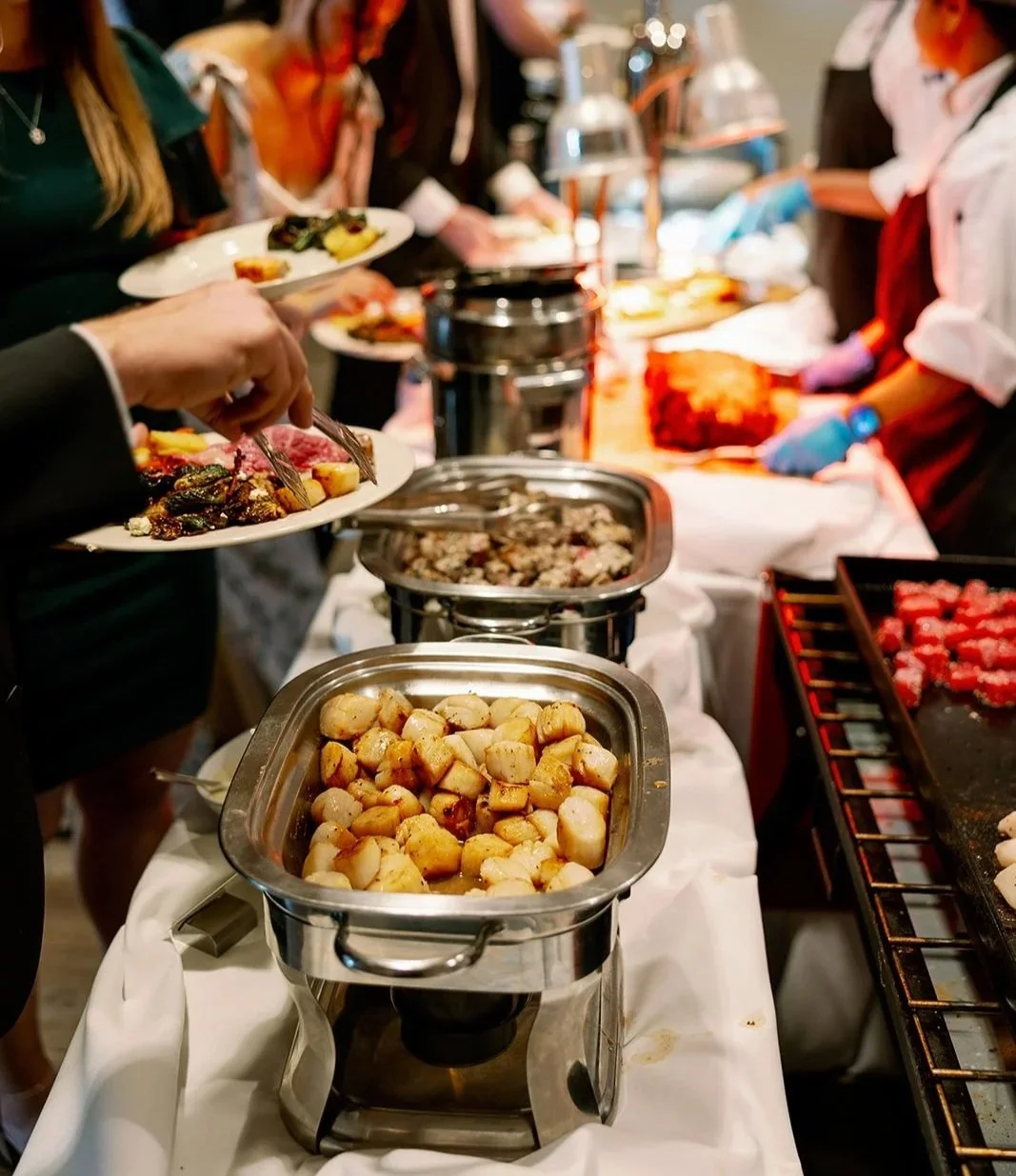 Guests serving themselves at a buffet with various hot foods and appetizers.