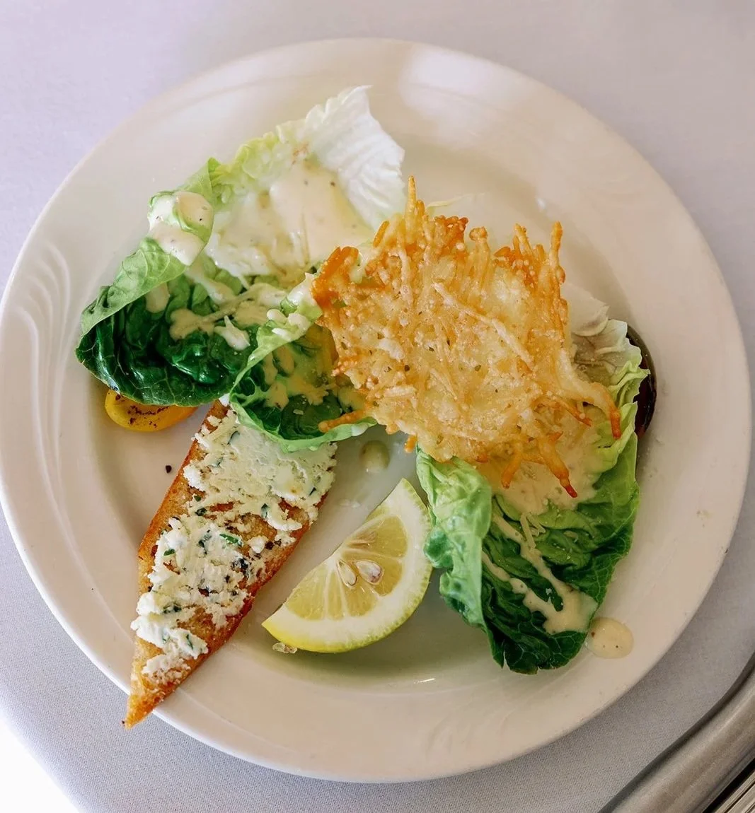 Salad with mixed greens, fried onion, lemon wedge, slice of blue cheese, and a breadstick topped with blue cheese crumbles.