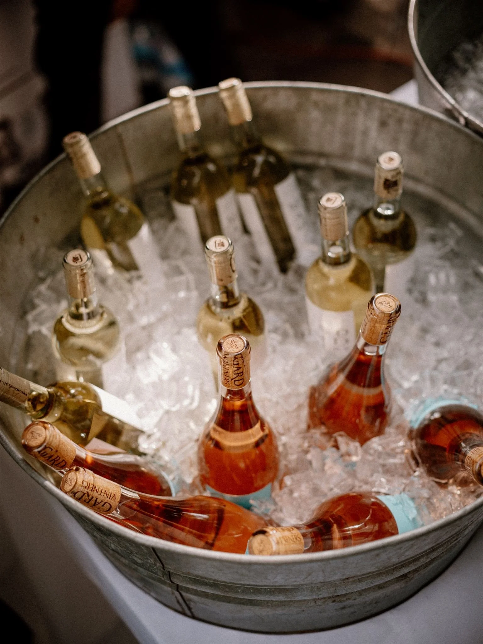 Glass bottles of rosé wine chilling in a metal ice bucket.