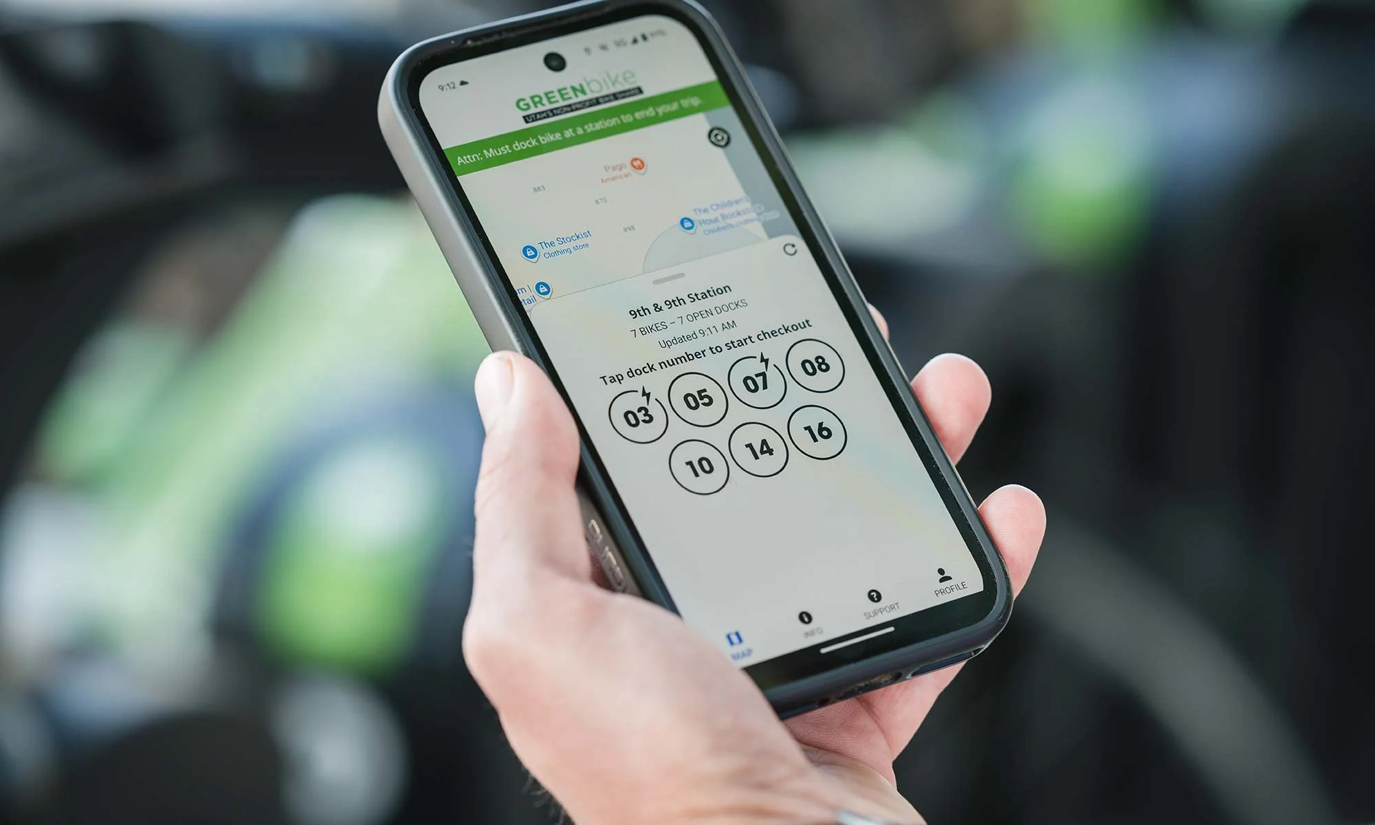 Person's hand holding a cell phone with the GreenBike app