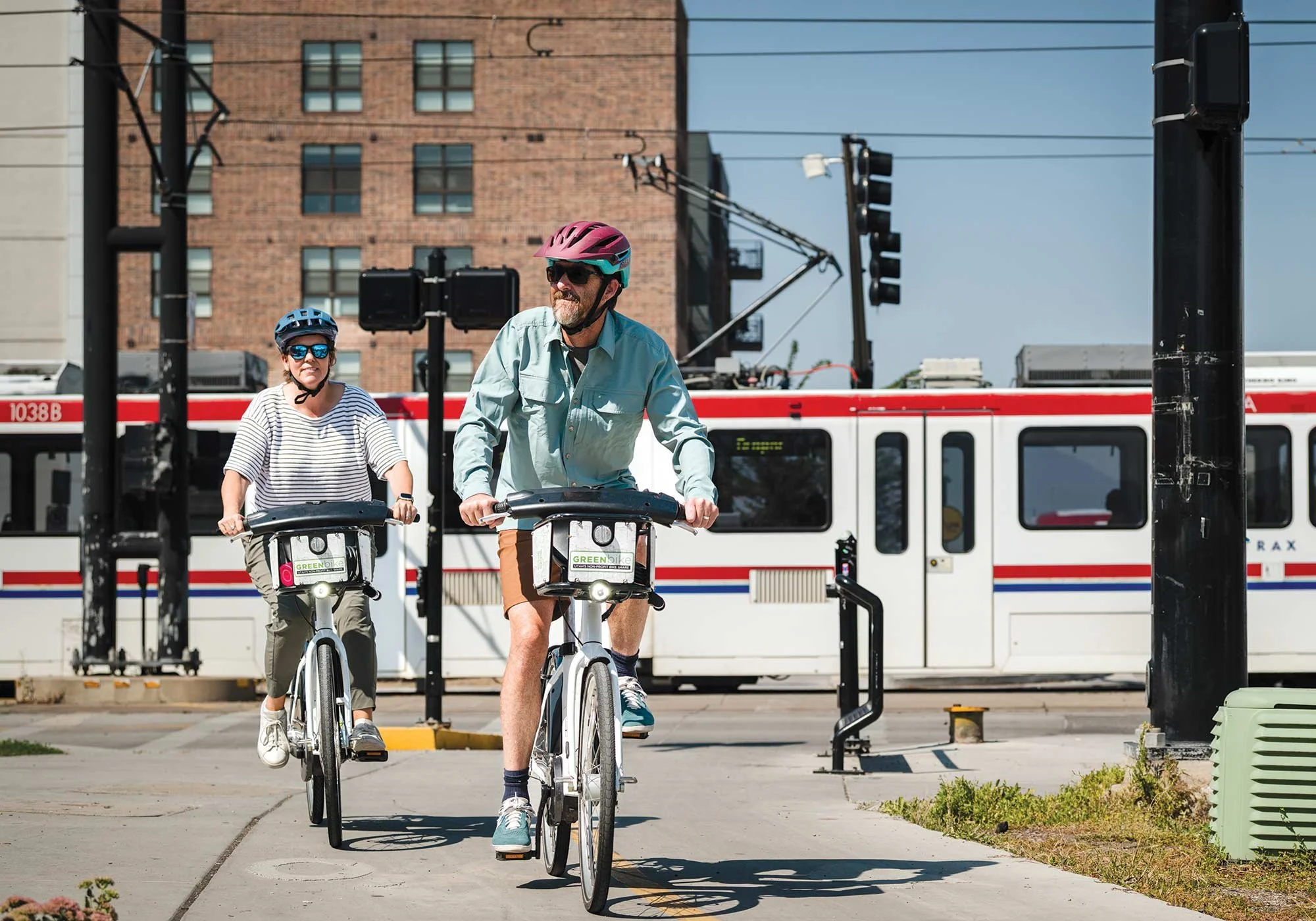 Husband and wife riding bikes with helmets and train in background
