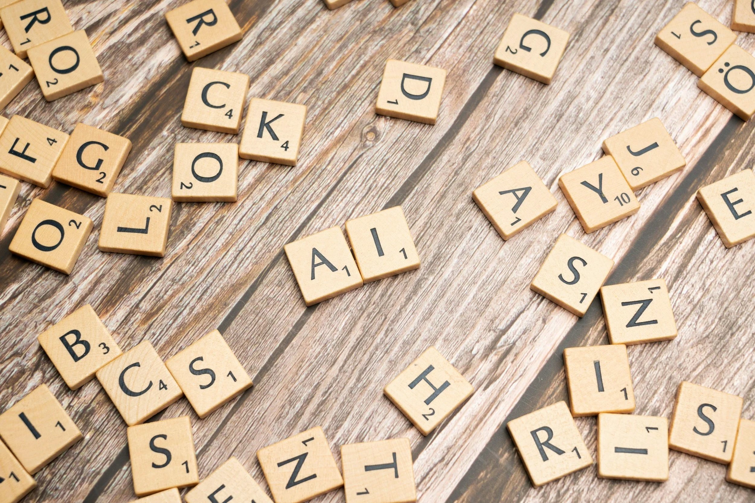 Les lettres du jeu de Scrabble dispersées sur une table en bois, avec quelques lettres formant le mot 'AIC'