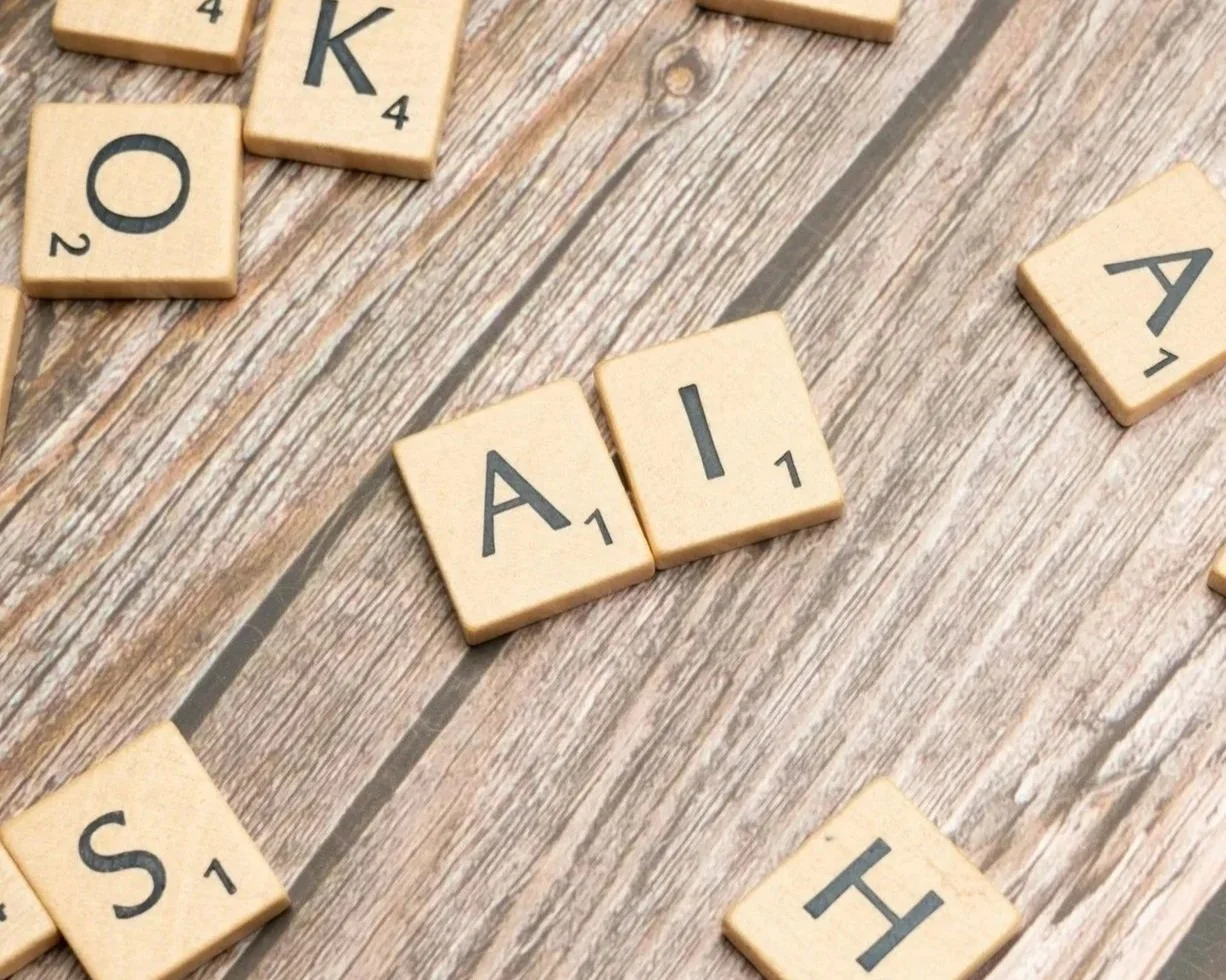 Mosaïque de tuiles en bois avec des lettres formant le mot 'AIDE' sur un fond en bois.