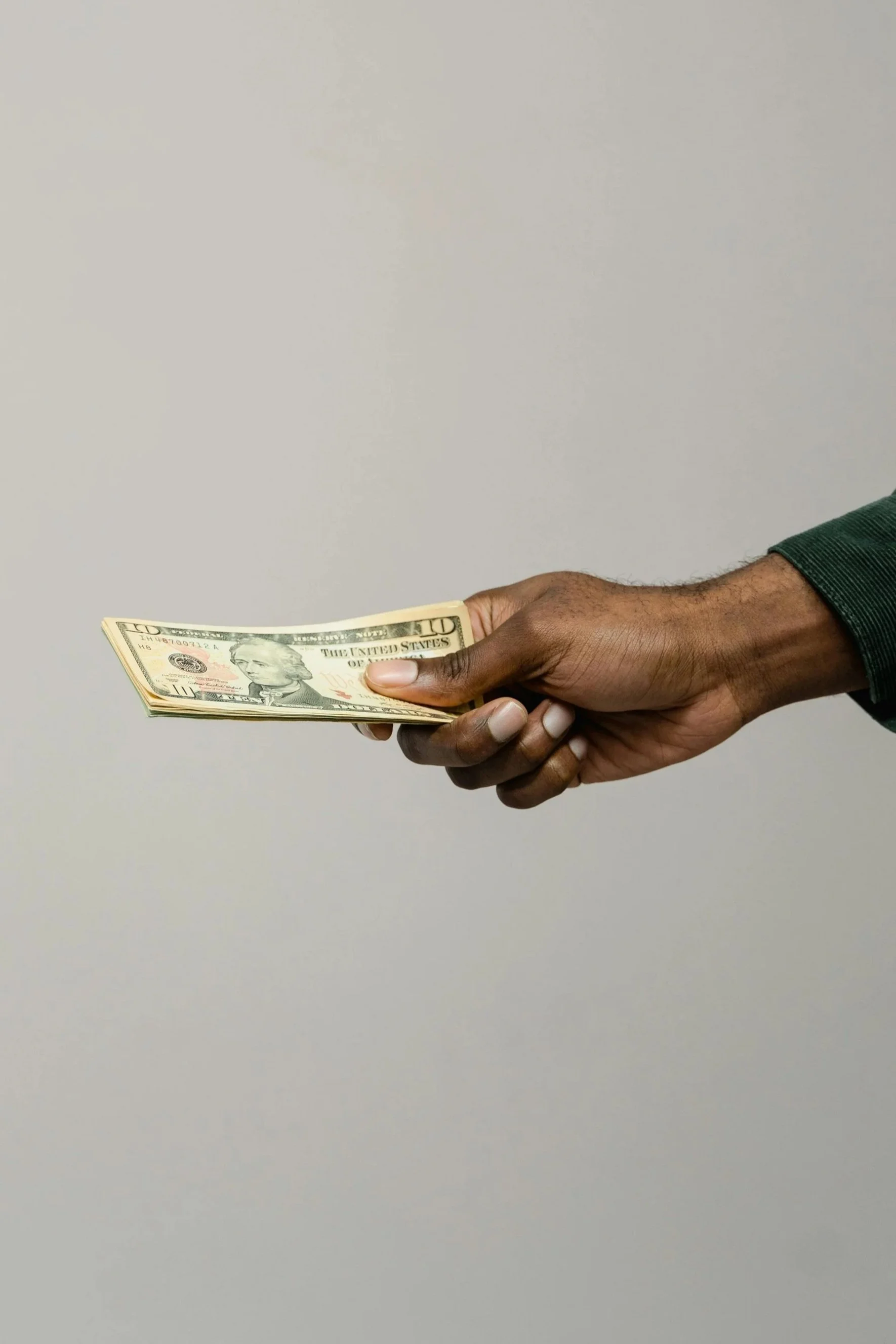 Une main tenant un paquet de billets de dix dollars des États-Unis