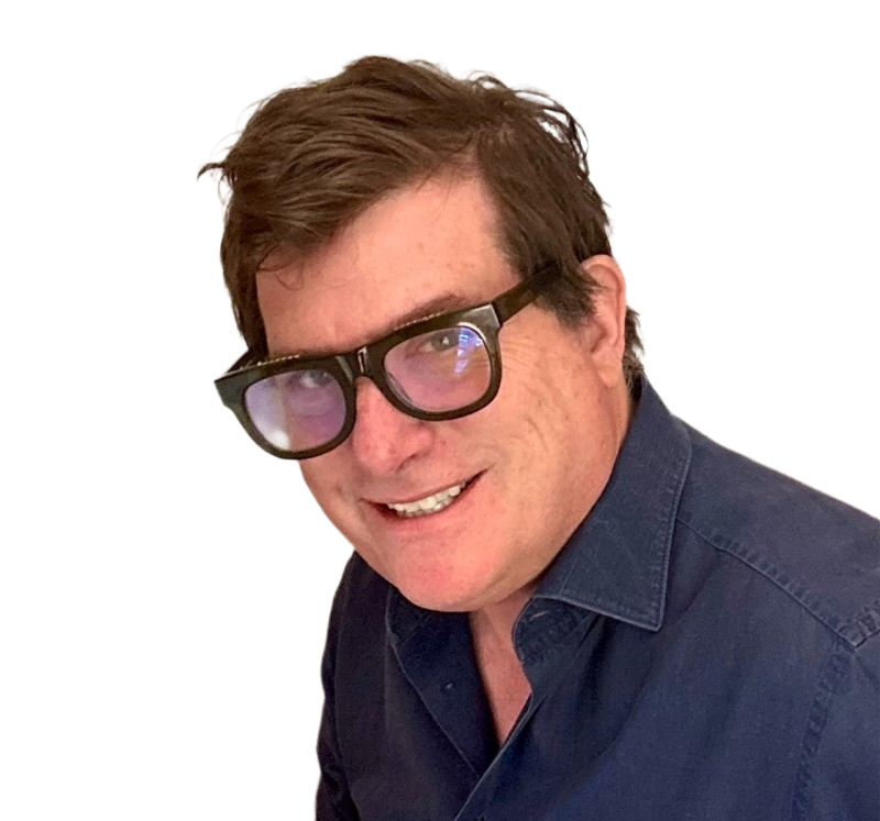 A man with brown hair wearing black glasses with purple-tinted lenses and a navy blue shirt, smiling at the camera.