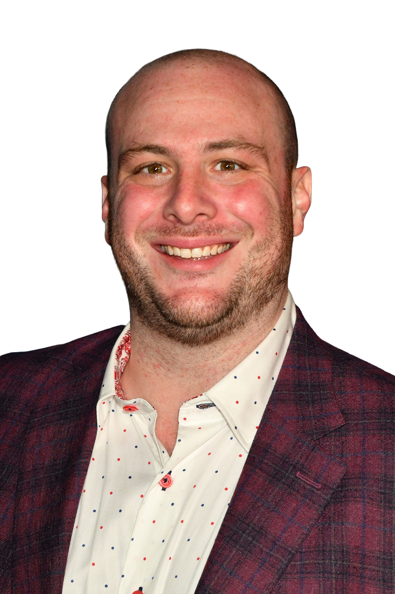 A smiling man with short hair, facial hair, and wearing a white shirt with small dots and a plaid blazer.